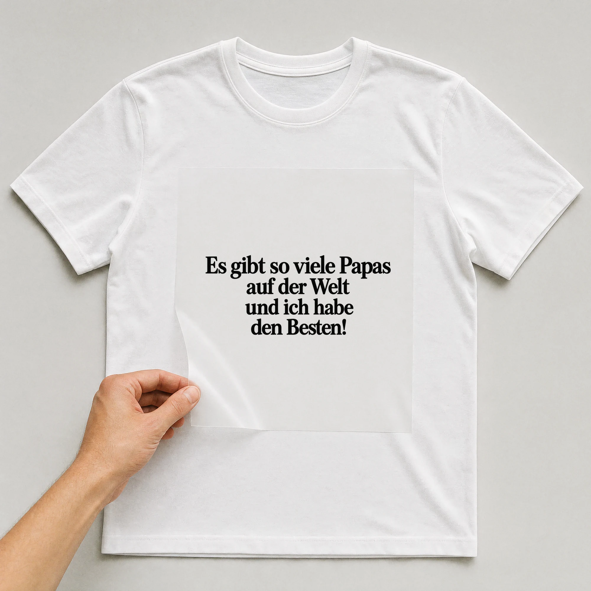 Bügelbild „Es gibt so viele Papas auf der Welt und ich habe den Besten!“ auf weißem T-Shirt, Folie wird aufgelegt
