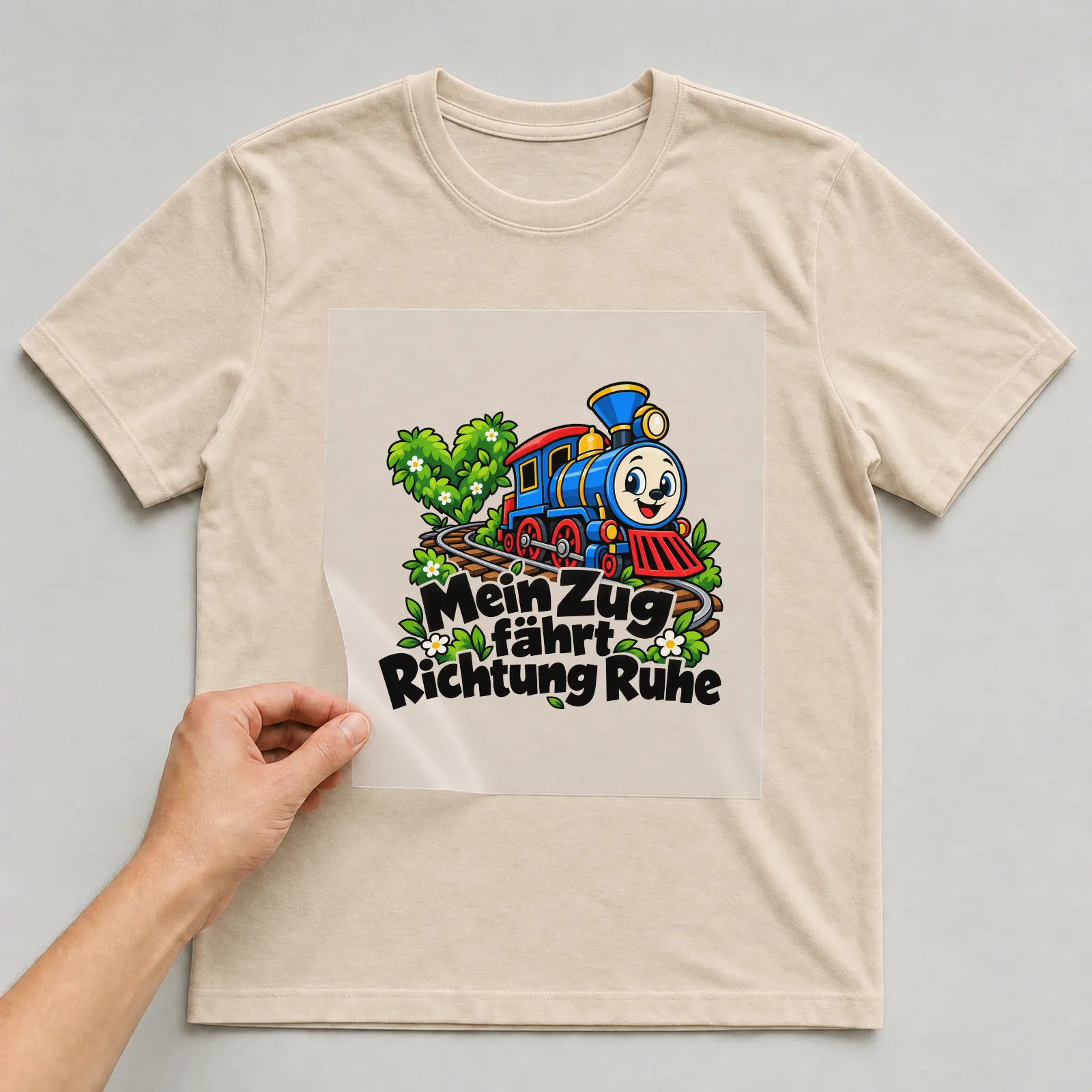 Bügelbild „Mein Zug fährt Richtung Ruhe“ auf beigem T-Shirt, Folie wird aufgelegt