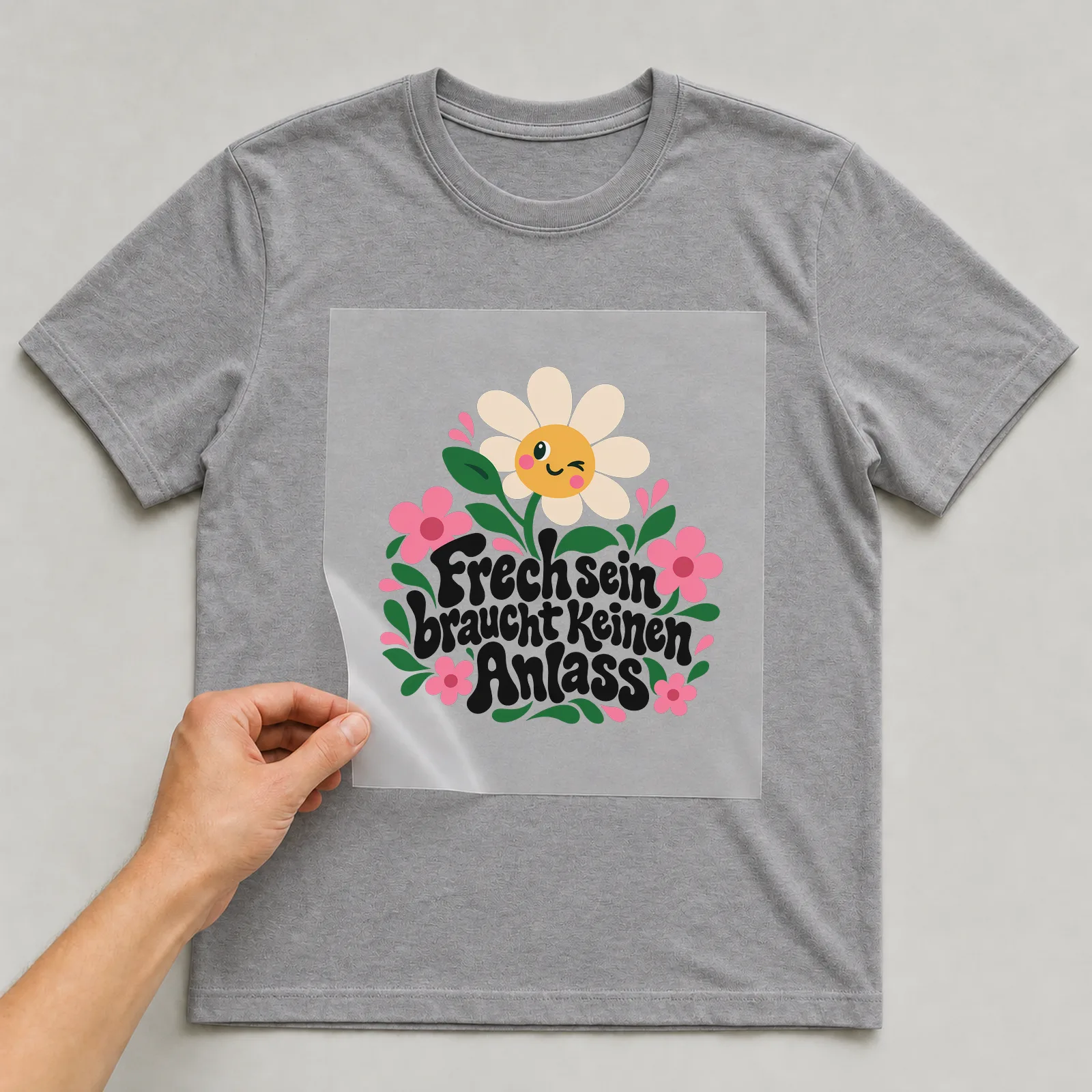 Bügelbild „Frechsein braucht keinen Anlass“ auf grauem T-Shirt, Folie wird aufgelegt