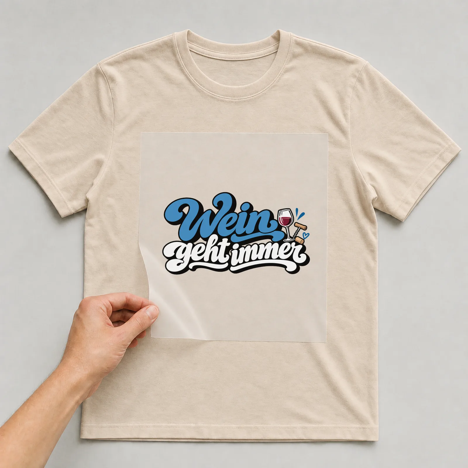 Bügelbild „Wein geht immer“ auf beigem T-Shirt, Folie wird aufgelegt