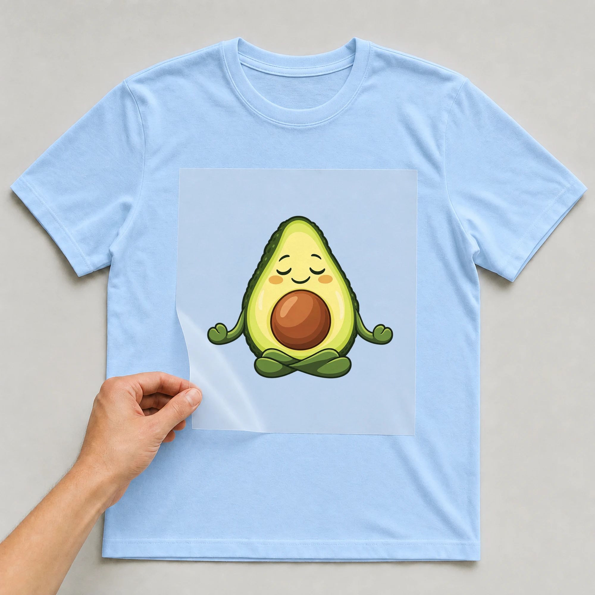 Bügelbild „Yogacado“ auf babyblauem T-Shirt, Folie wird aufgelegt