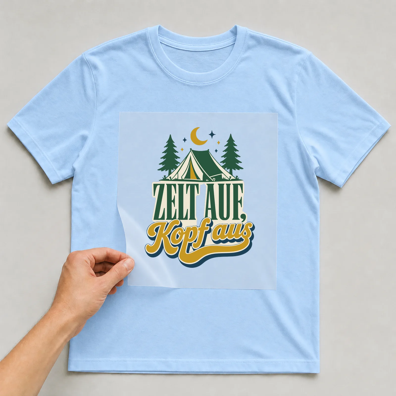 Bügelbild Zelt auf, Kopf aus auf hellblauem T-Shirt, Folie wird aufgelegt