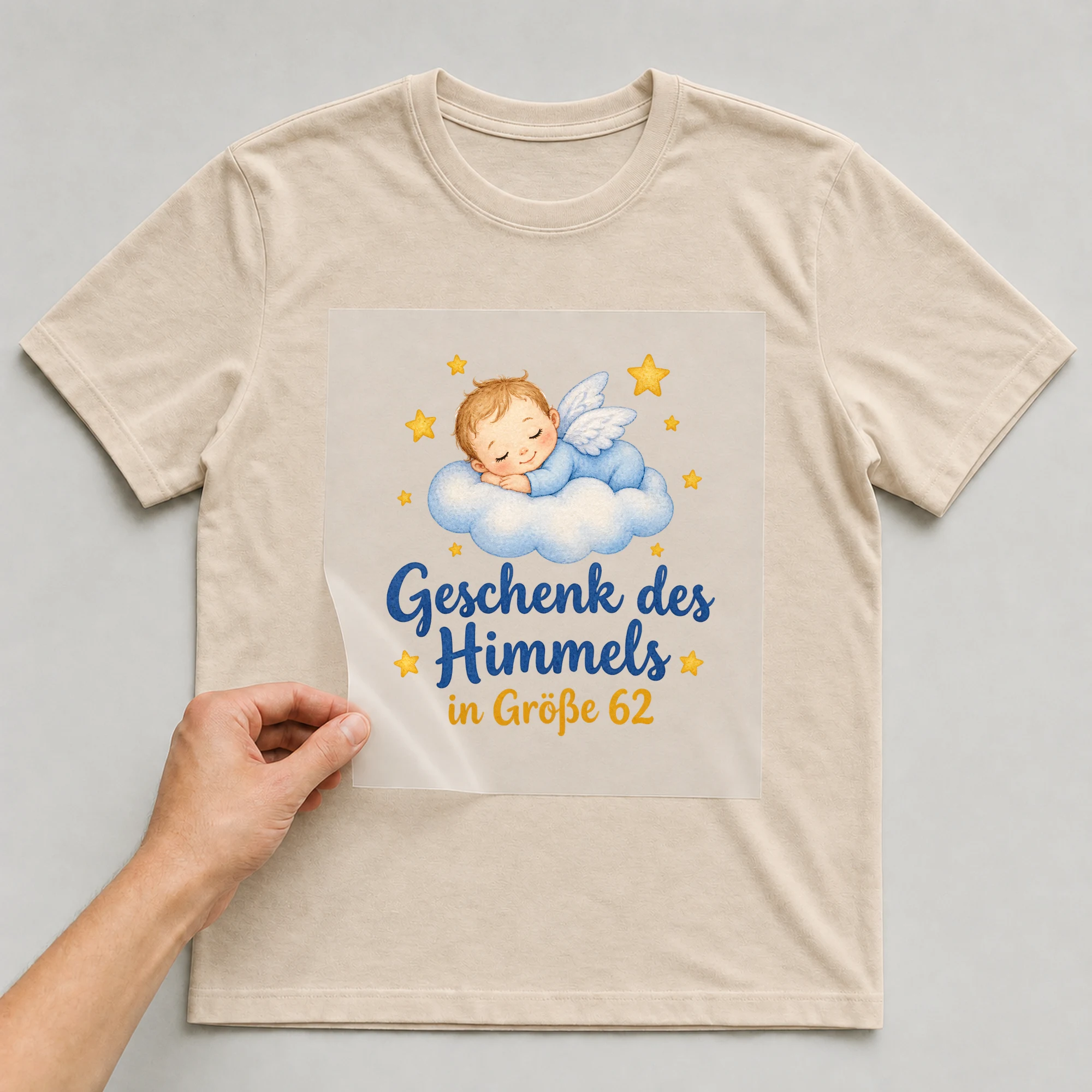 Bügelbild „Geschenk des Himmels in Größe 62“ auf beigem T-Shirt, Folie wird aufgelegt