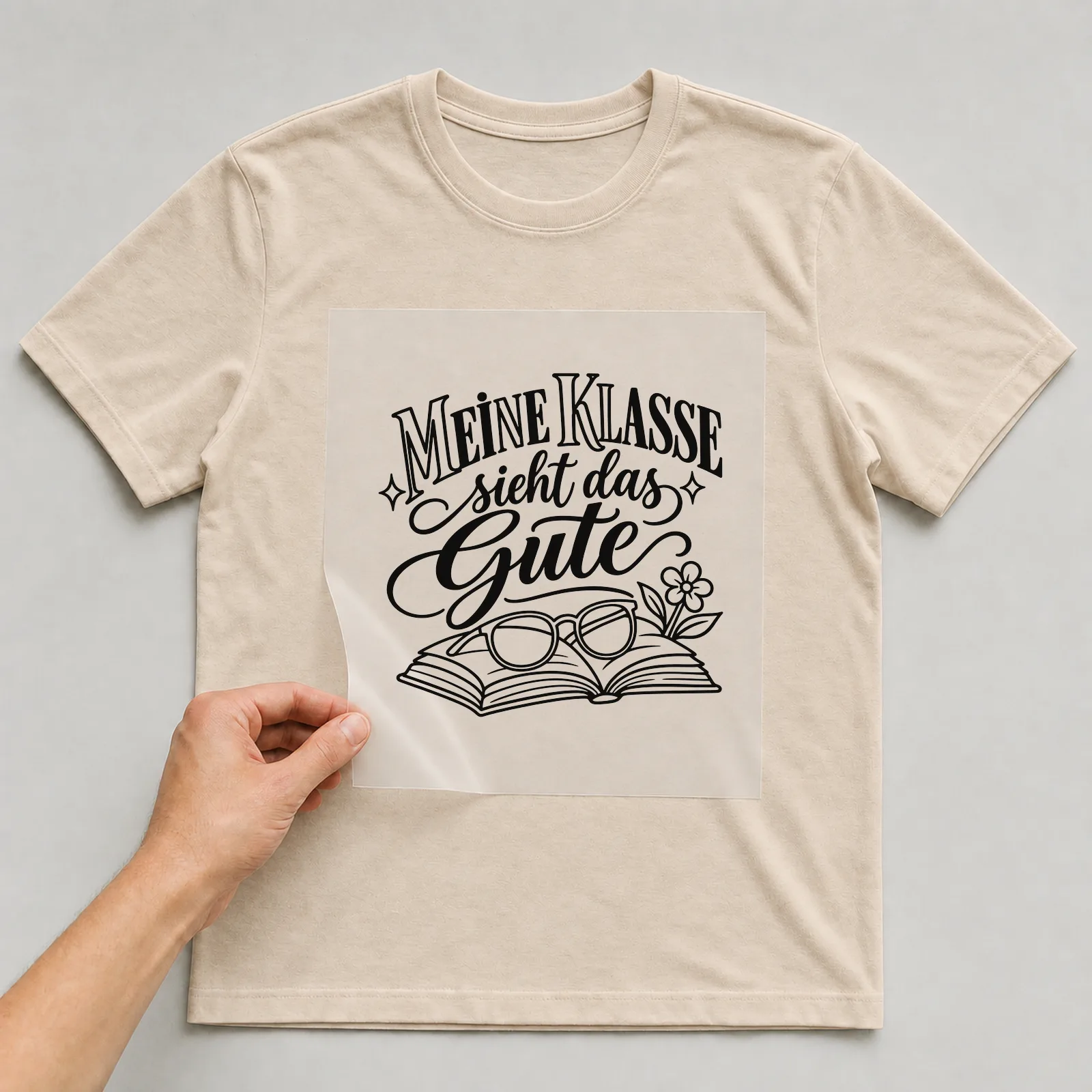 Bügelbild „Meine Klasse sieht das Gute“ auf beigem T-Shirt, Folie wird aufgelegt