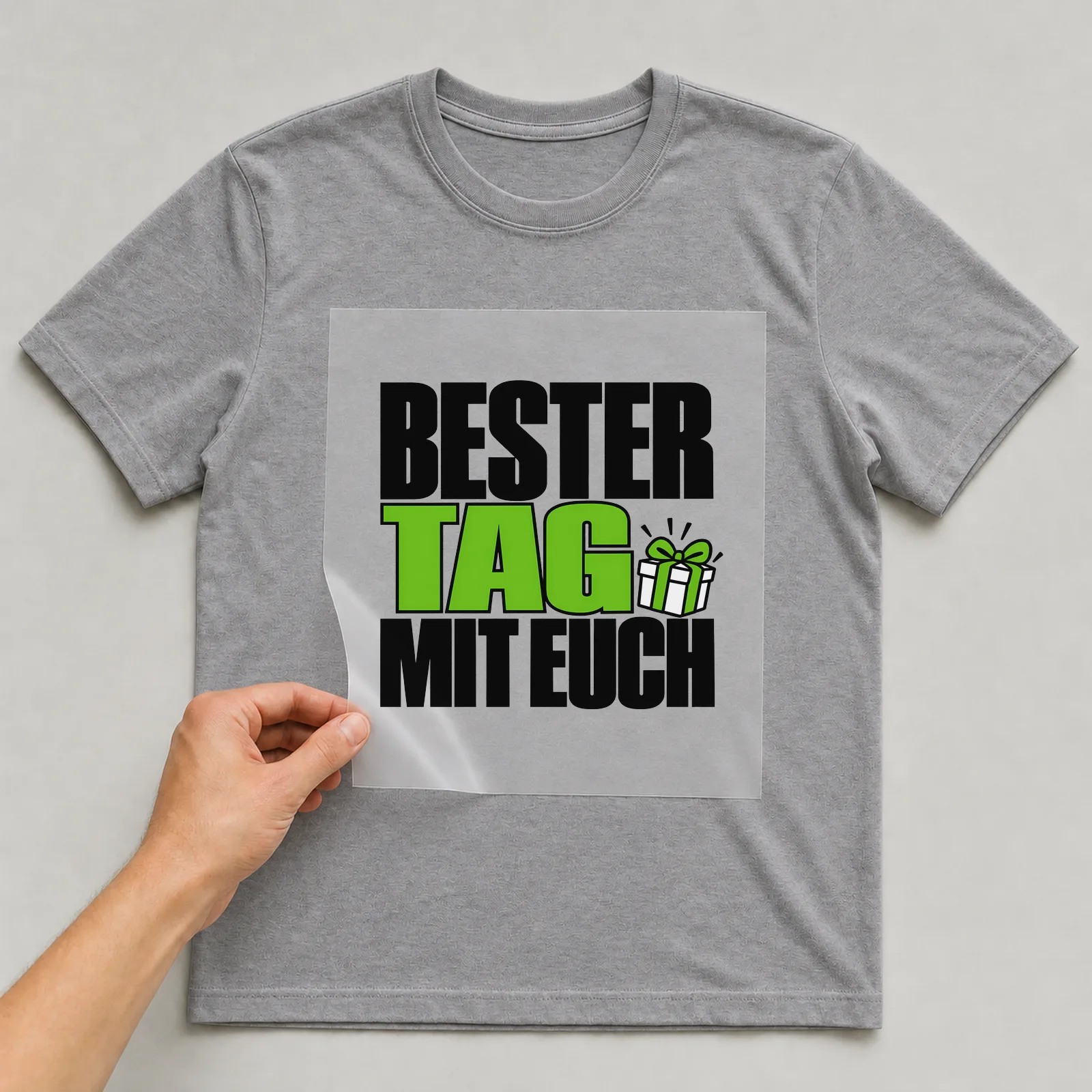 Bügelbild „Bester Tag mit euch“ auf grauem T-Shirt, Folie wird aufgelegt