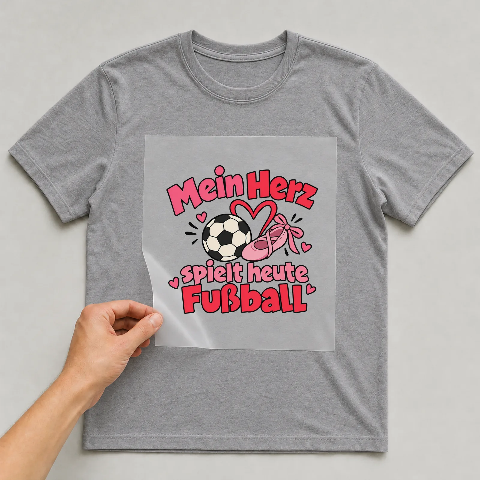 Bügelbild „Mein Herz spielt heute Fußball“ auf grauem T-Shirt, Folie wird aufgelegt