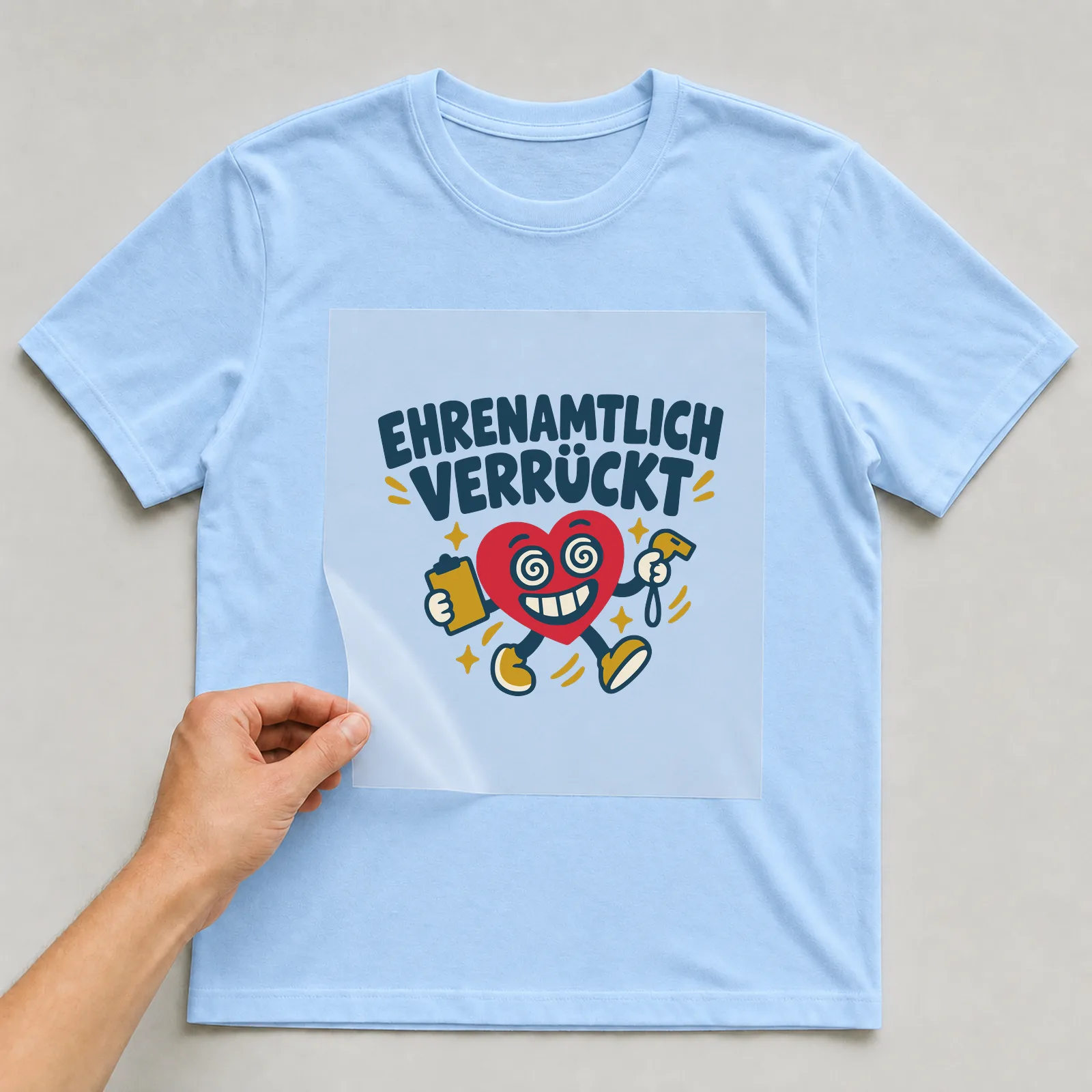 Bügelbild Ehrenamtlich verrückt auf hellblauem T-Shirt, Folie wird aufgelegt