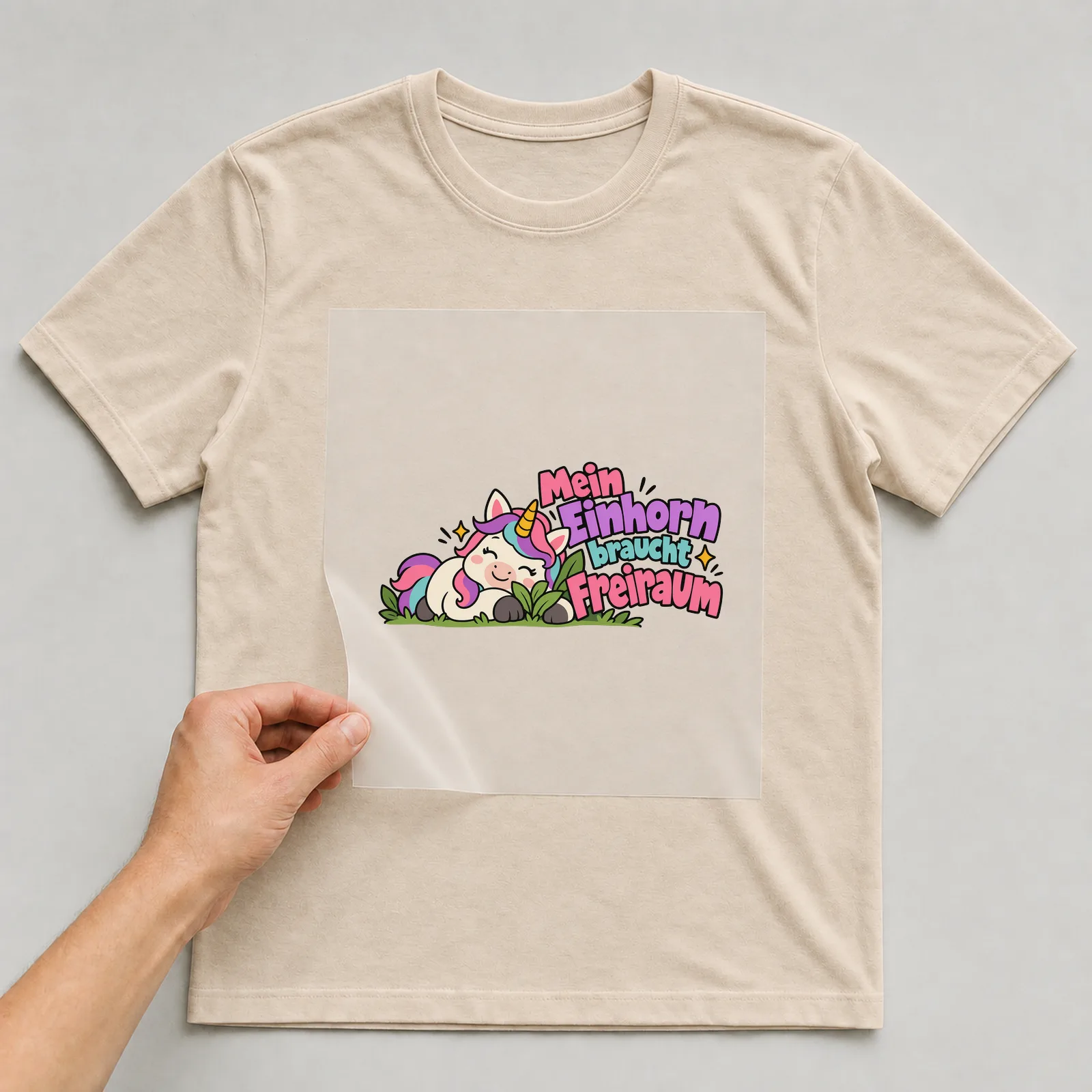 Bügelbild „Mein Einhorn braucht Freiraum“ auf beigem T-Shirt, Folie wird aufgelegt