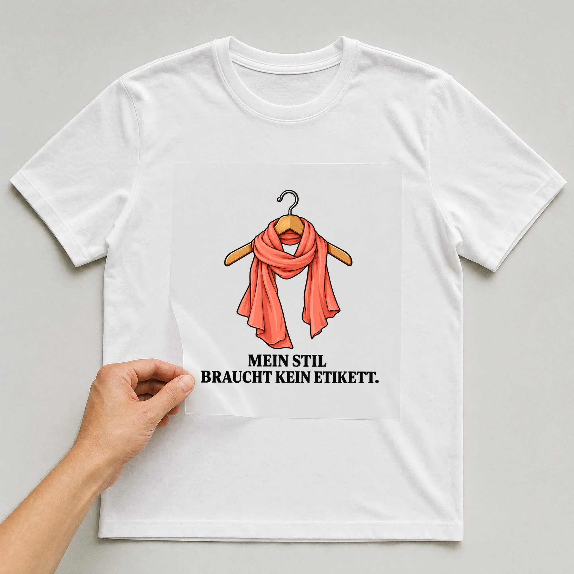 Bügelbild „MEIN STIL BRAUCHT KEIN ETIKETT.“ auf weißem T-Shirt, Folie wird aufgelegt