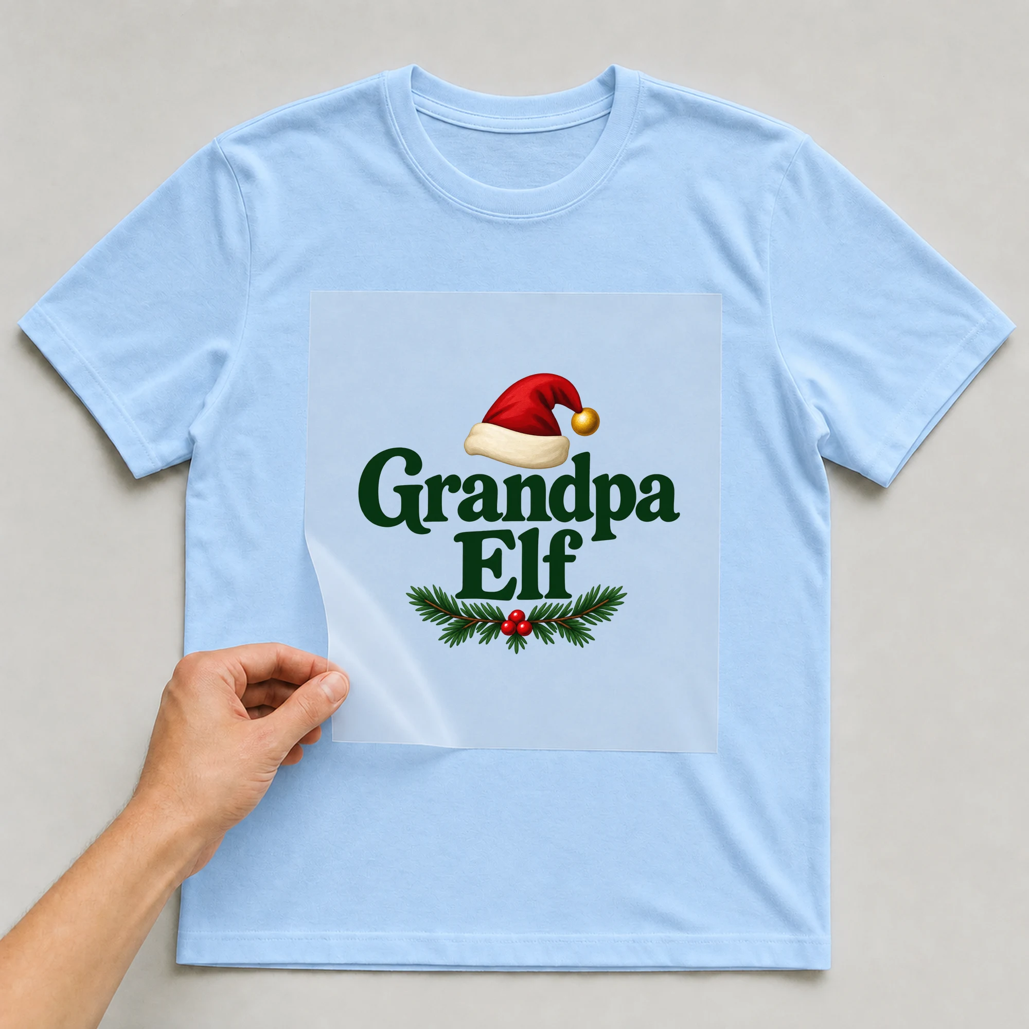 Bügelbild „Grandpa Elf“ auf babyblauem T-Shirt, Folie wird aufgelegt