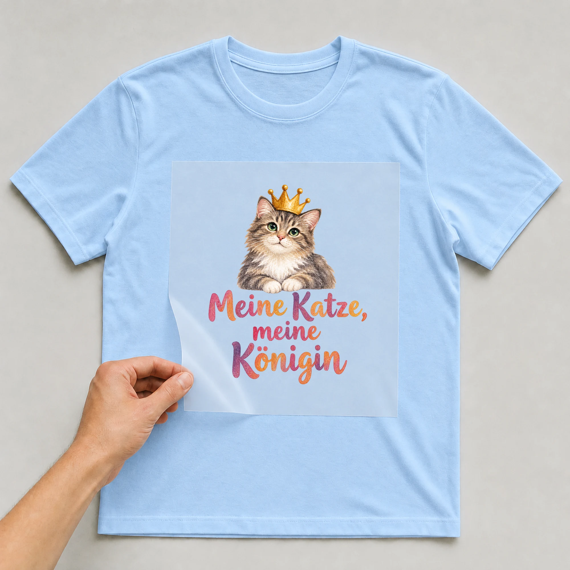 Bügelbild „Meine Katze, meine Königin“ auf babyblauem T-Shirt, Folie wird aufgelegt
