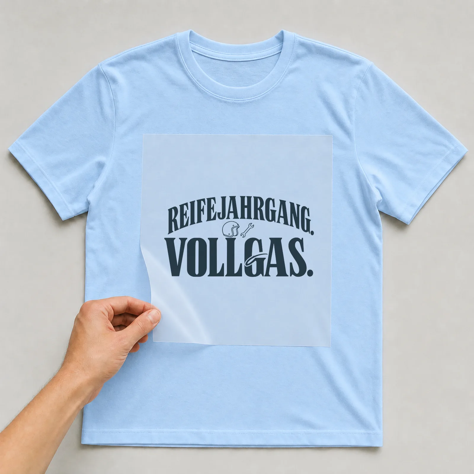 Bügelbild „Reifejahrgang. Vollgas.“ (Schrift Konturen, Nr. 2) auf hellblauem T-Shirt, Folie wird aufgelegt