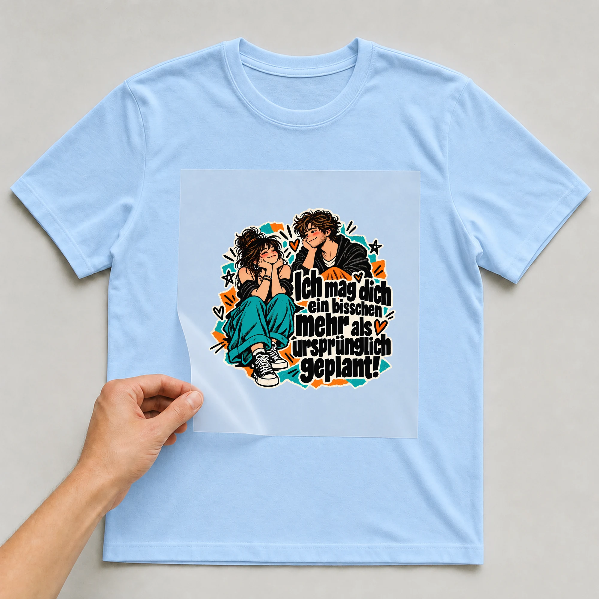 Bügelbild „Ich mag dich ein bisschen mehr“ auf babyblauem T-Shirt, Folie wird aufgelegt