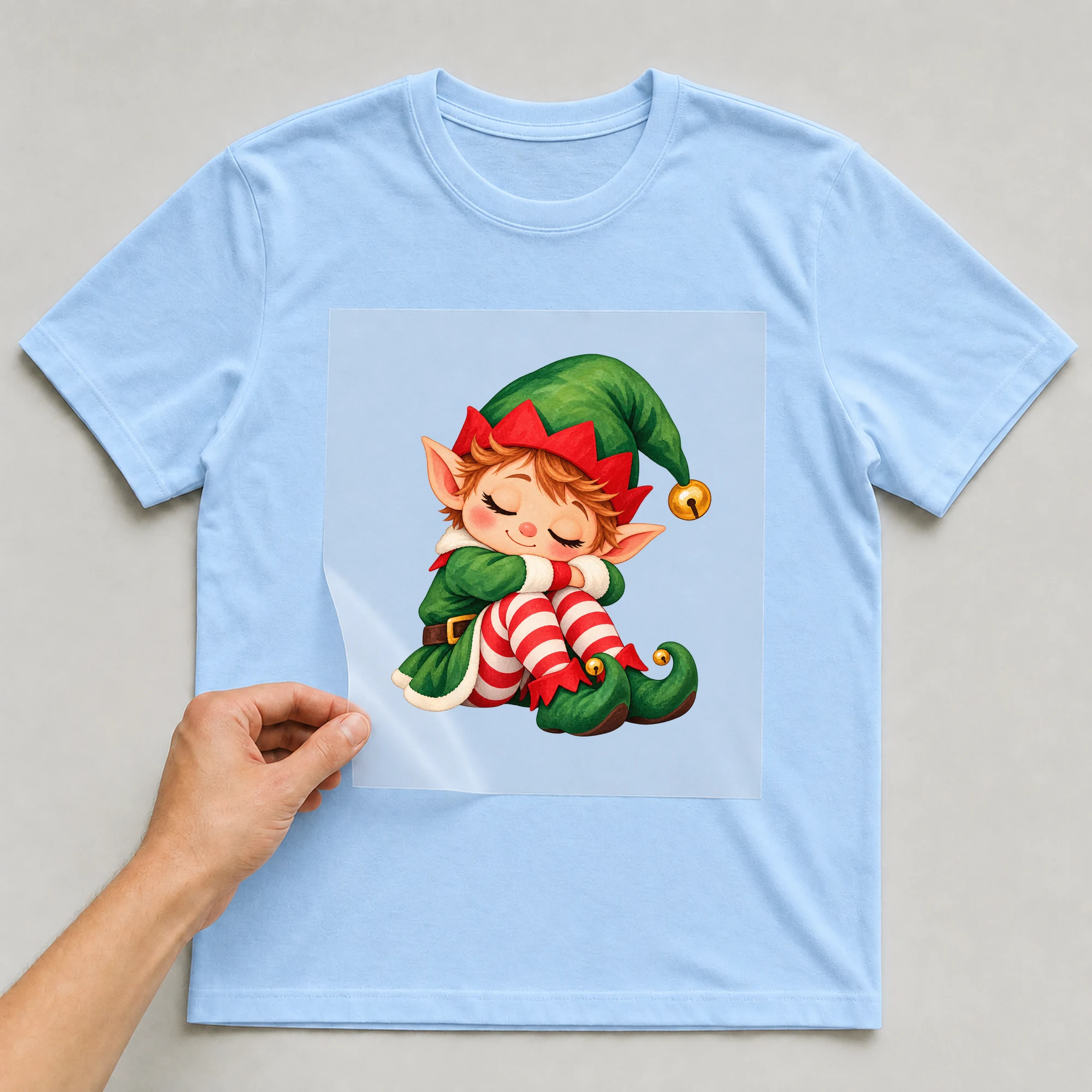 Bügelbild „Müde Elfe“ auf babyblauem T-Shirt, Folie wird aufgelegt
