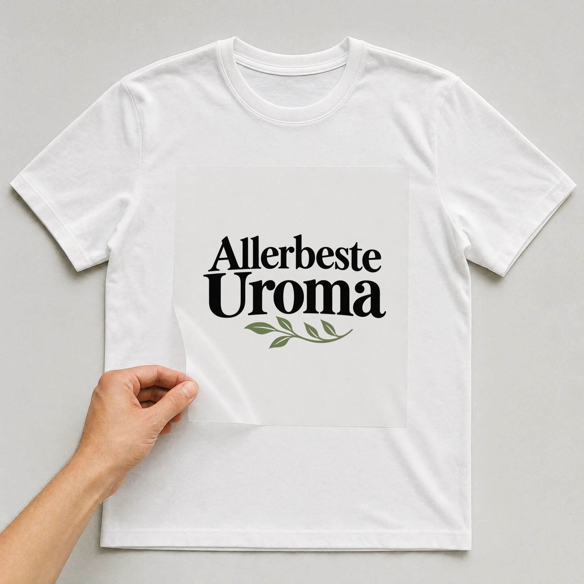 Bügelbild „Allerbeste Uroma“ auf weißem T-Shirt, Folie wird aufgelegt