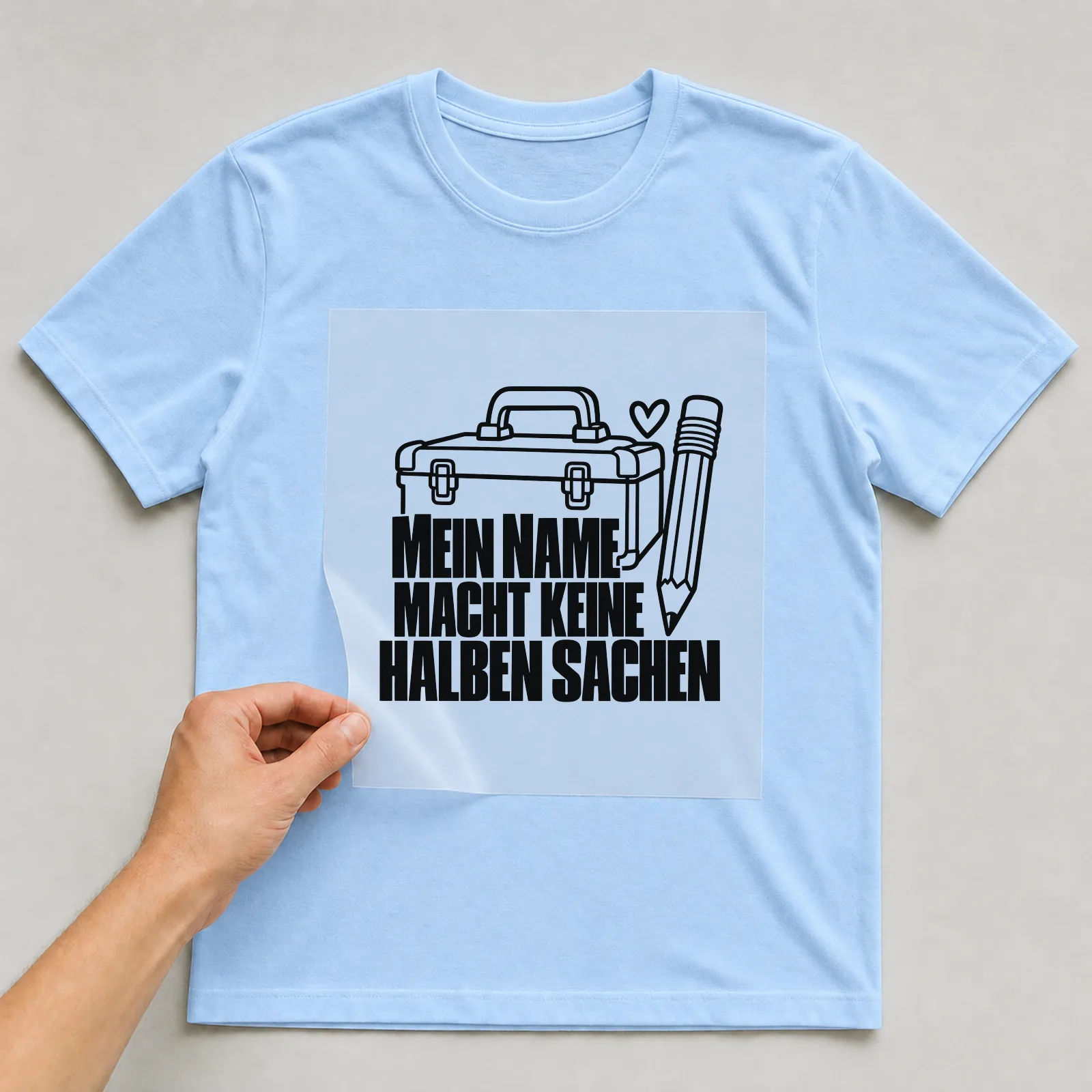 Bügelbild „Mein Name macht keine halben Sachen“ auf hellblauem T-Shirt, Folie wird aufgelegt
