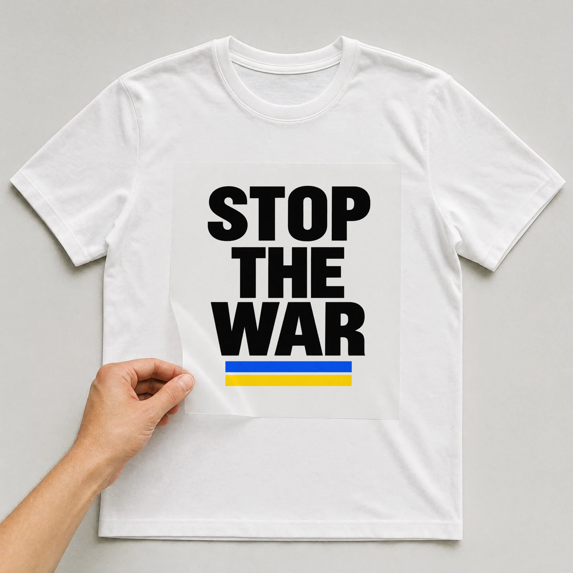 Bügelbild „STOP THE WAR“ auf weißem T-Shirt, Folie wird aufgelegt
