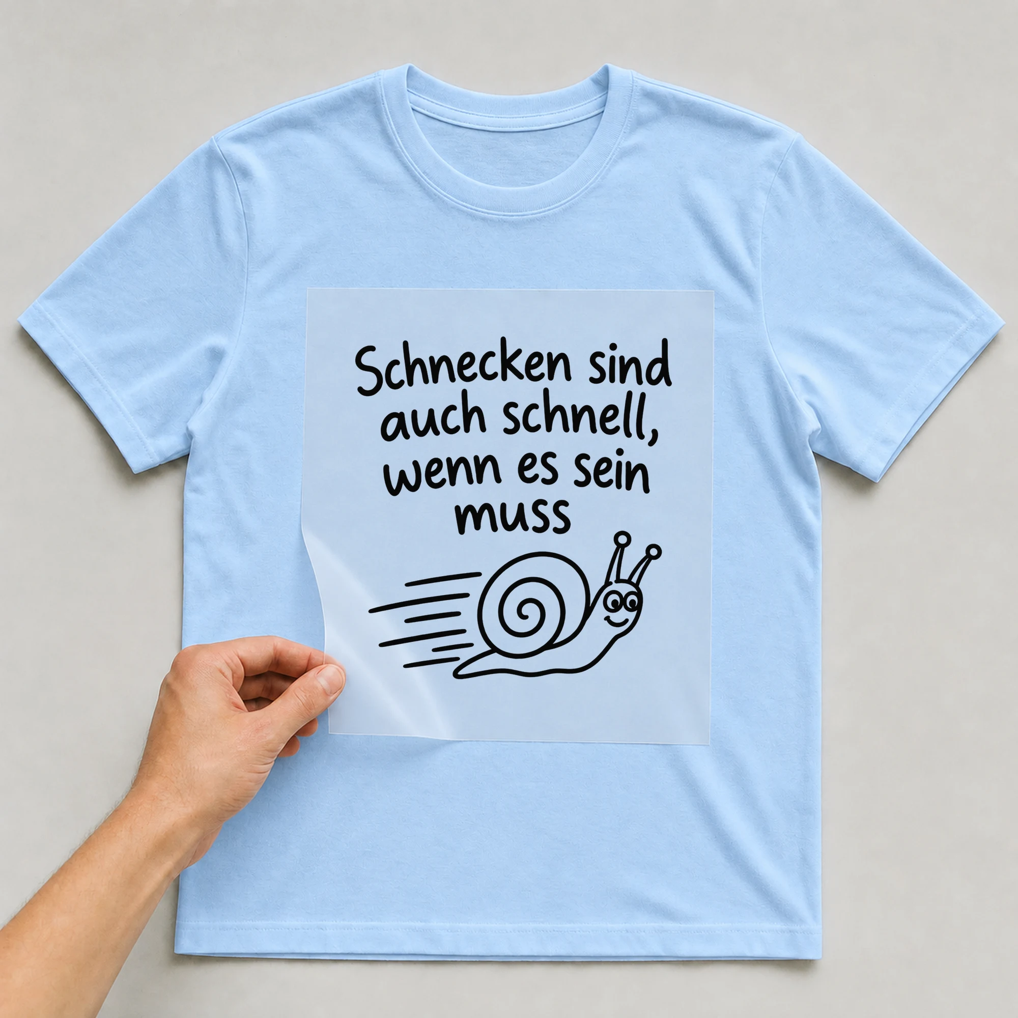 Bügelbild „Schnecken sind auch schnell, wenn es sein muss“ auf babyblauem T-Shirt, Folie wird aufgelegt
