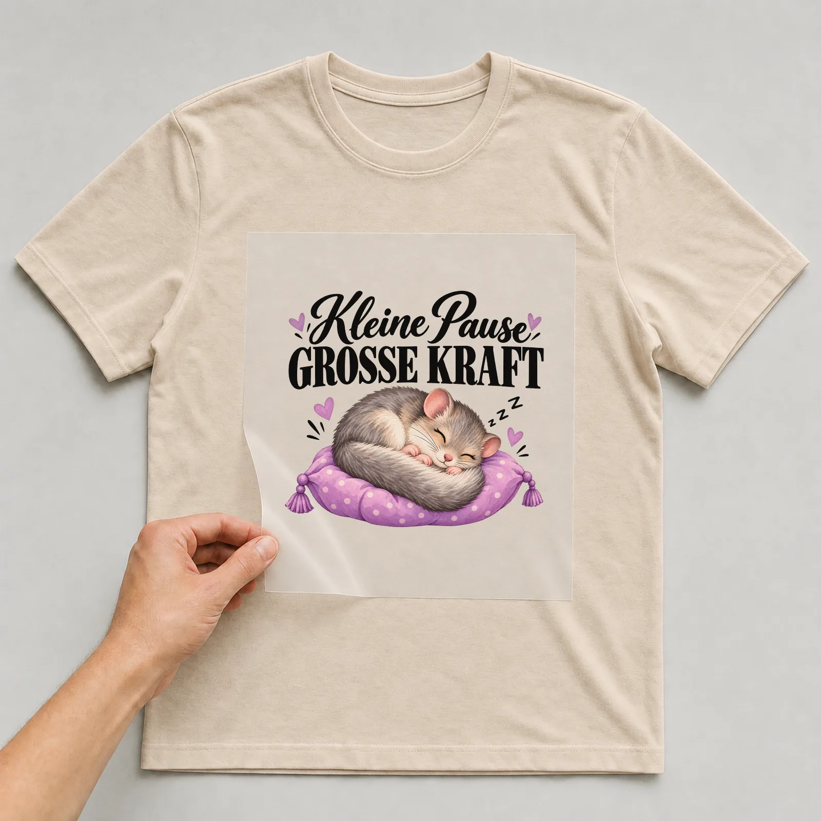 Bügelbild „Kleine Pause große Kraft“ auf beigem T-Shirt, Folie wird aufgelegt