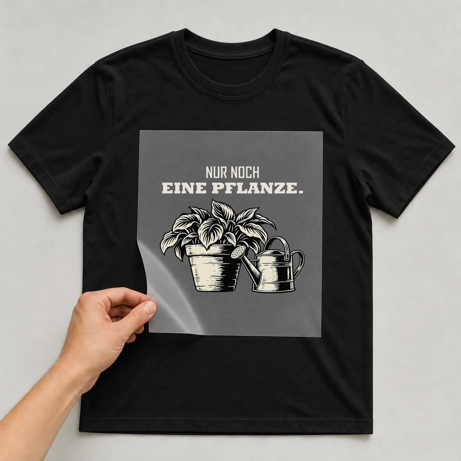Bügelbild „Nur noch eine Pflanze“ auf schwarzem T-Shirt, Folie wird aufgelegt
