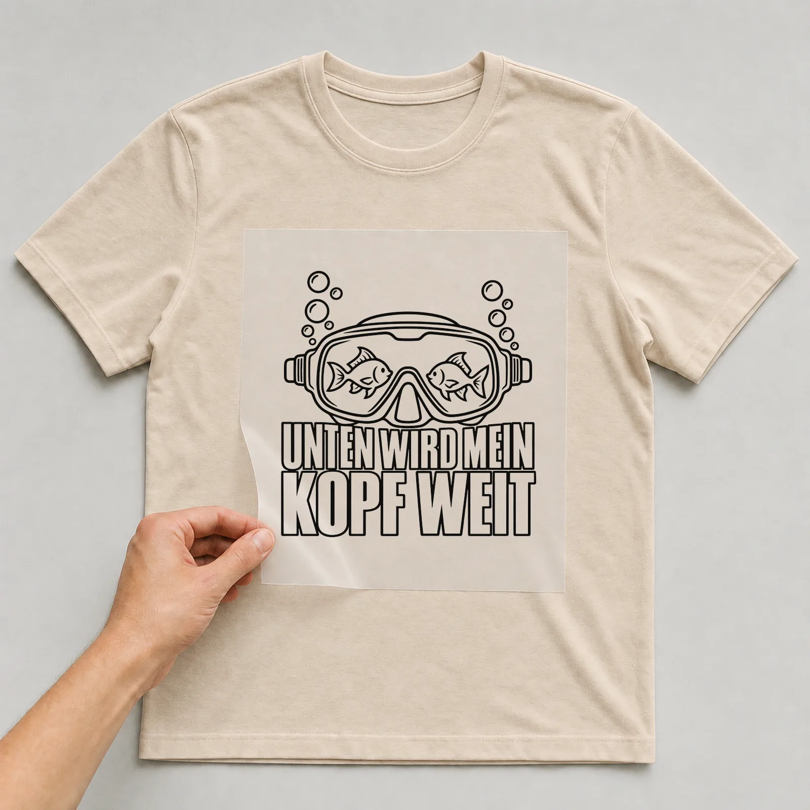 Bügelbild „Unten wird mein Kopf weit“ auf beigem T-Shirt, Folie wird aufgelegt