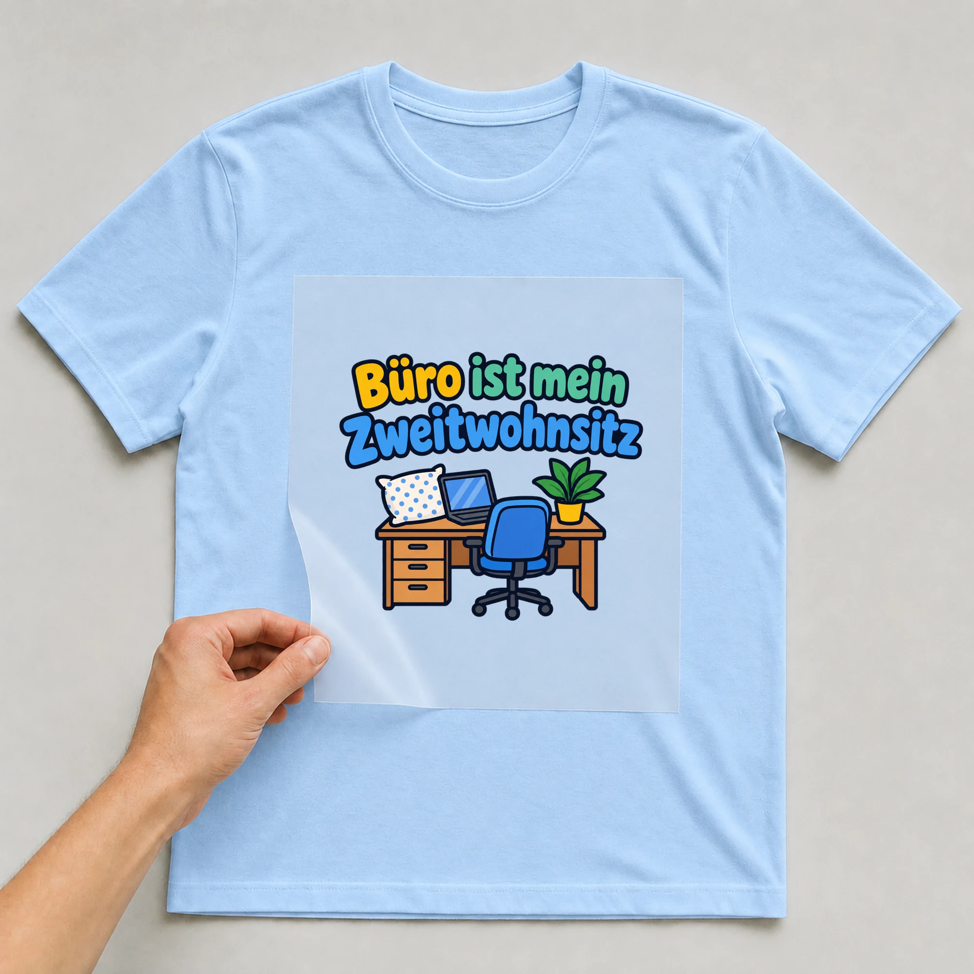 Bügelbild „Büro ist mein Zweitwohnsitz“ auf babyblauem T-Shirt, Folie wird aufgelegt
