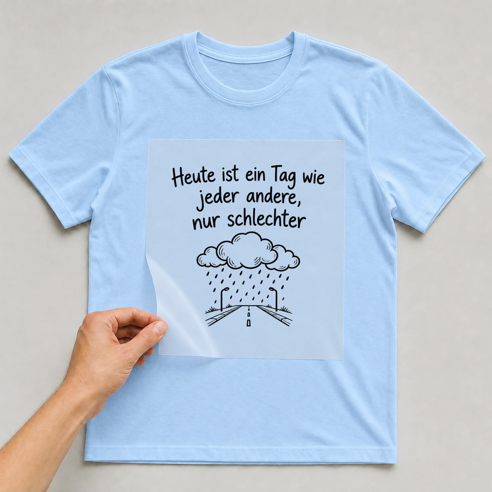 Bügelbild „Heute ist ein Tag wie jeder andere, nur schlechter“ auf babyblauem T-Shirt, Folie wird aufgelegt