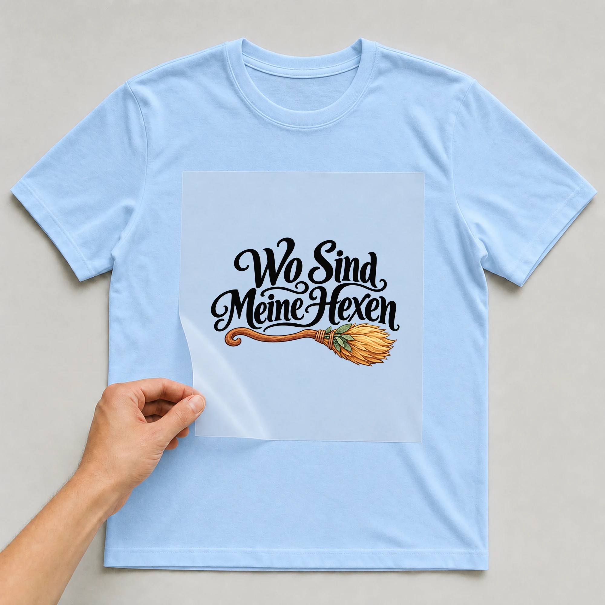 Bügelbild „Wo Sind Meine Hexen“ auf babyblauem T-Shirt, Folie wird aufgelegt
