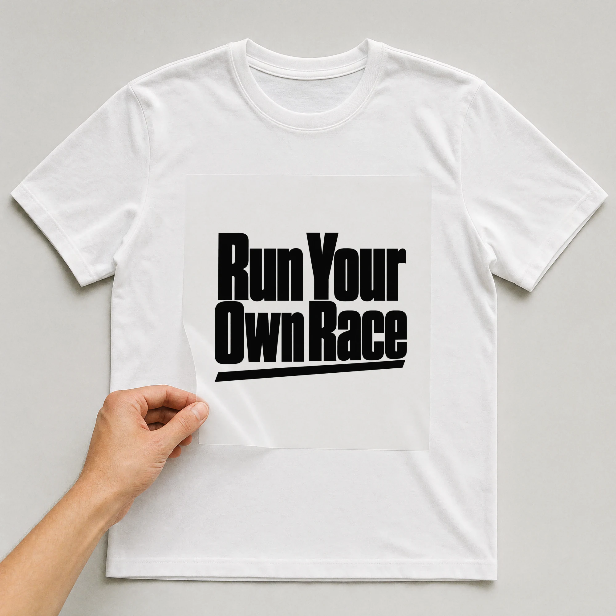 Bügelbild „Run Your Own Race“ auf weißem T-Shirt, Folie wird aufgelegt