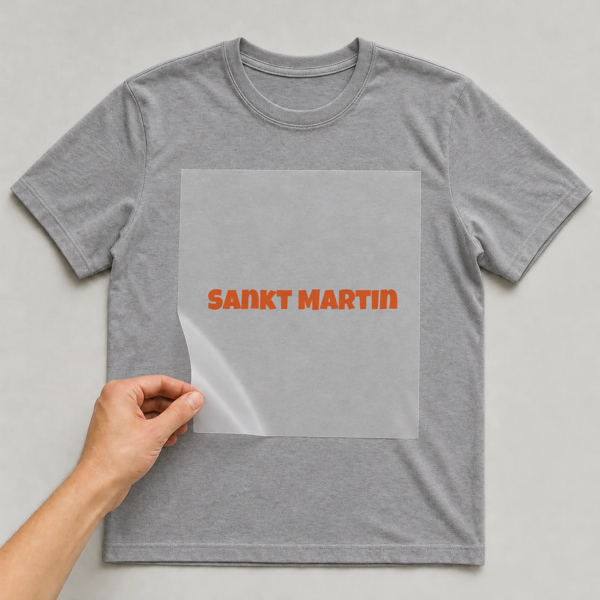 Bügelbild „Schriftzug Sankt Martin“ auf grauem T-Shirt, Folie wird aufgelegt