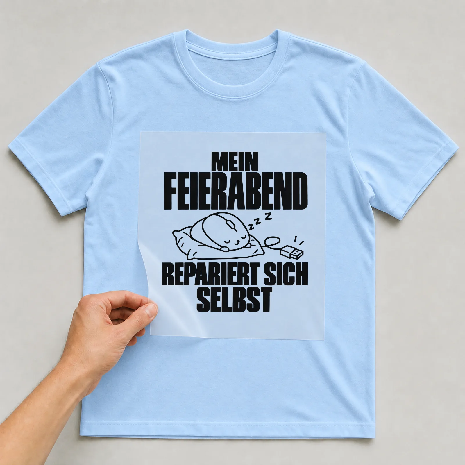 Bügelbild „Mein Feierabend repariert sich selbst“ auf hellblauem T-Shirt, Folie wird aufgelegt