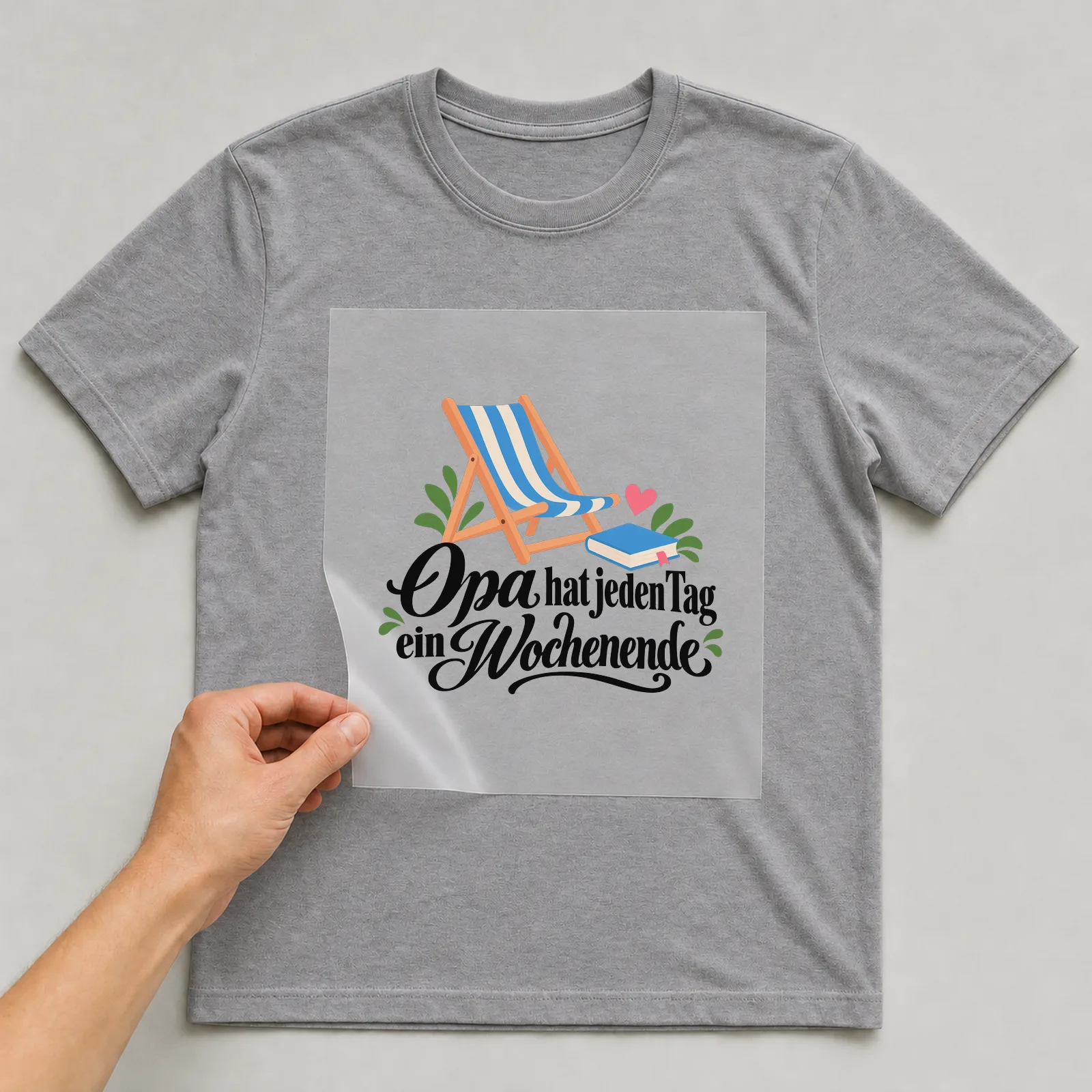 Bügelbild „Oma hat jeden Tag ein Wochenende“ auf grauem T-Shirt, Folie wird aufgelegt