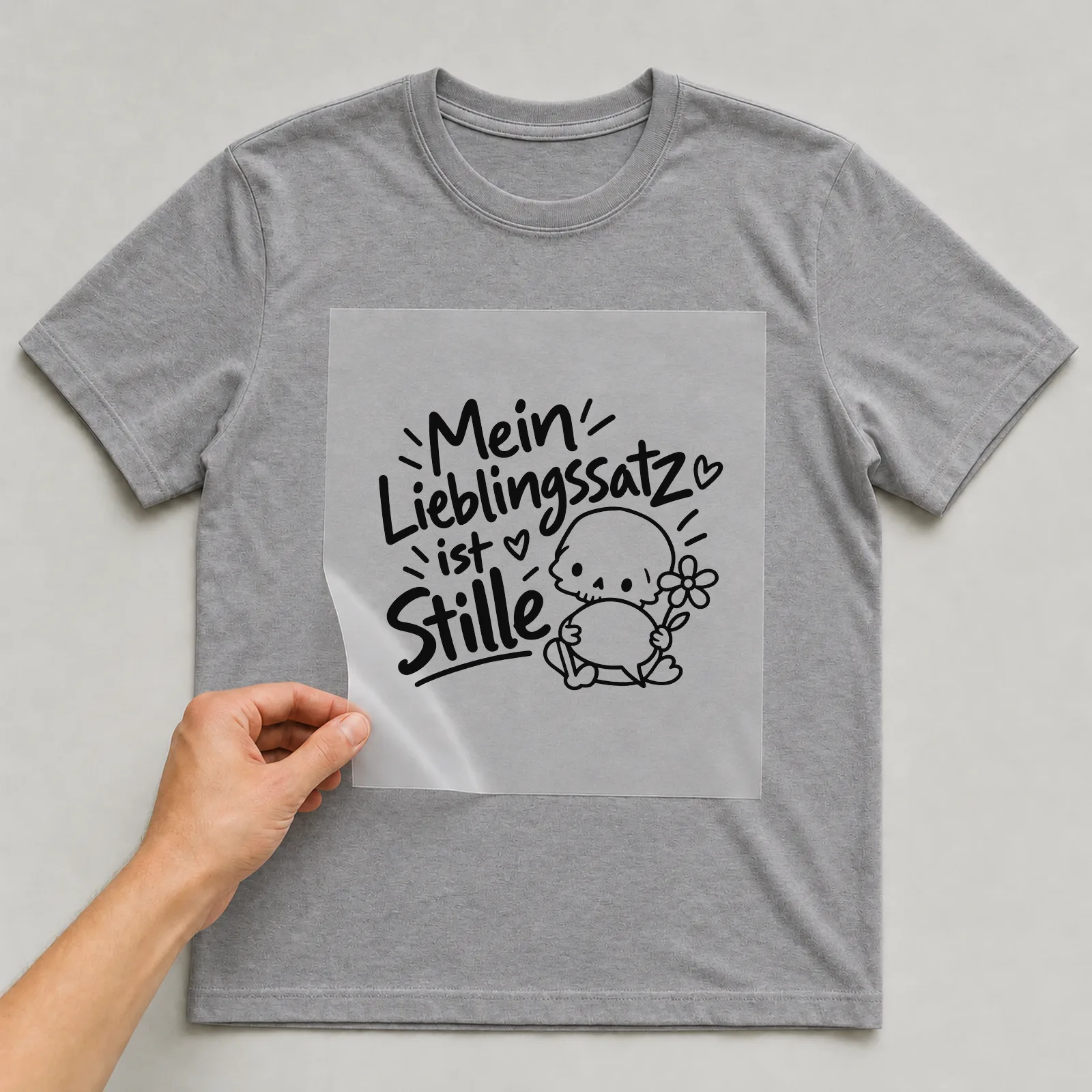 Bügelbild „Mein Lieblingssatz ist Stille“ auf grauem T-Shirt, Folie wird aufgelegt
