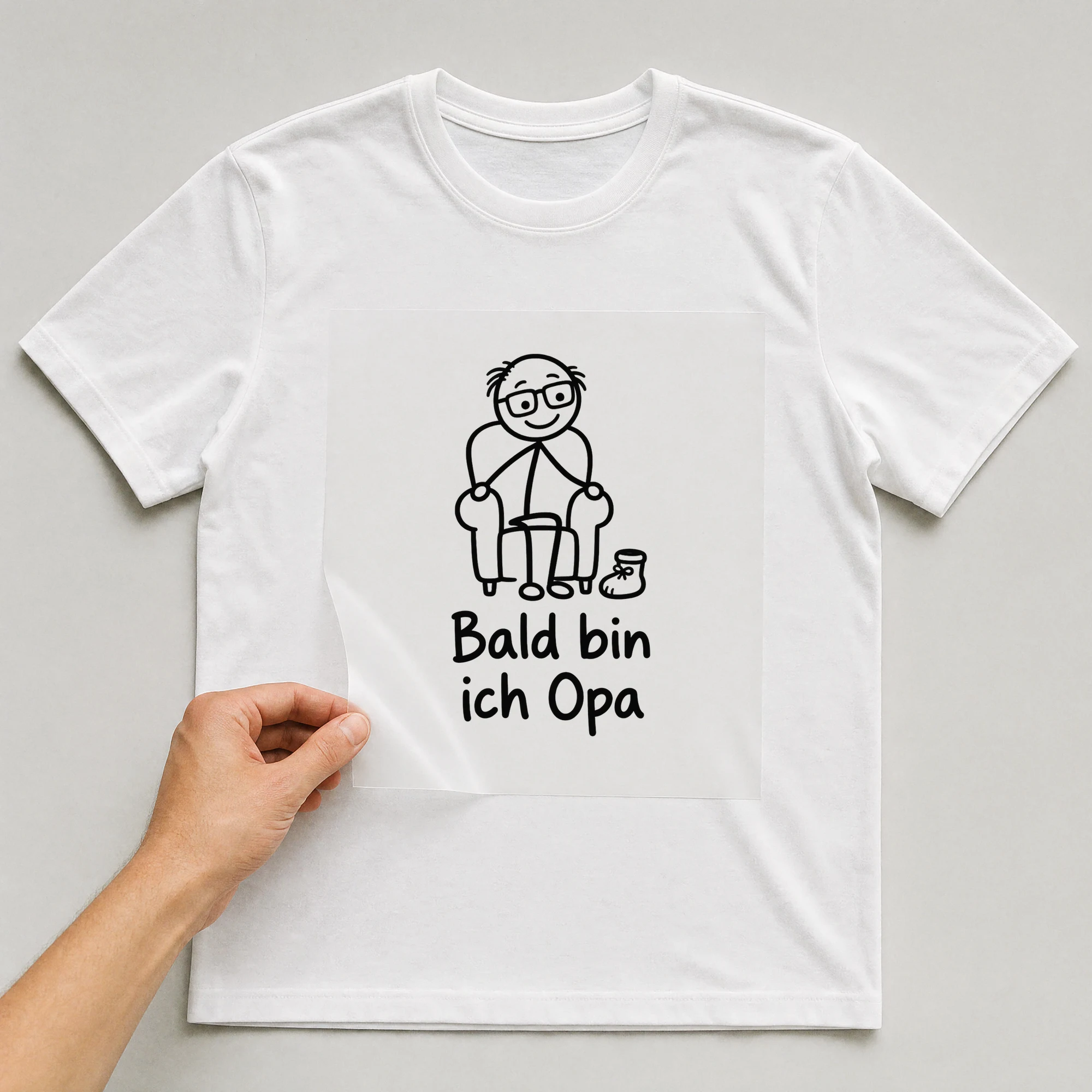 Bügelbild „Bald bin ich Opa“ auf weißem T-Shirt, Folie wird aufgelegt