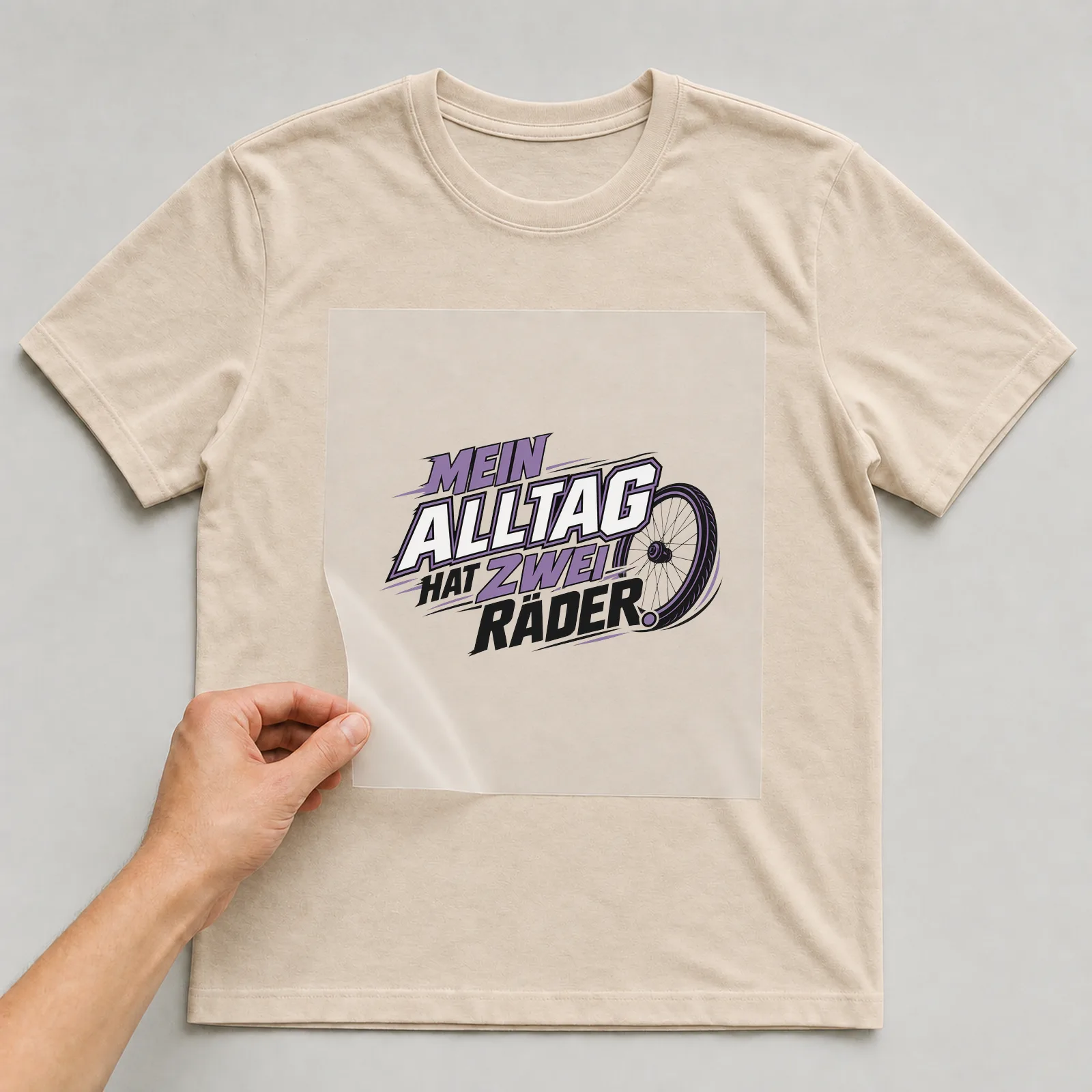 Bügelbild „Mein Alltag hat zwei Räder“ auf beigem T-Shirt, Folie wird aufgelegt