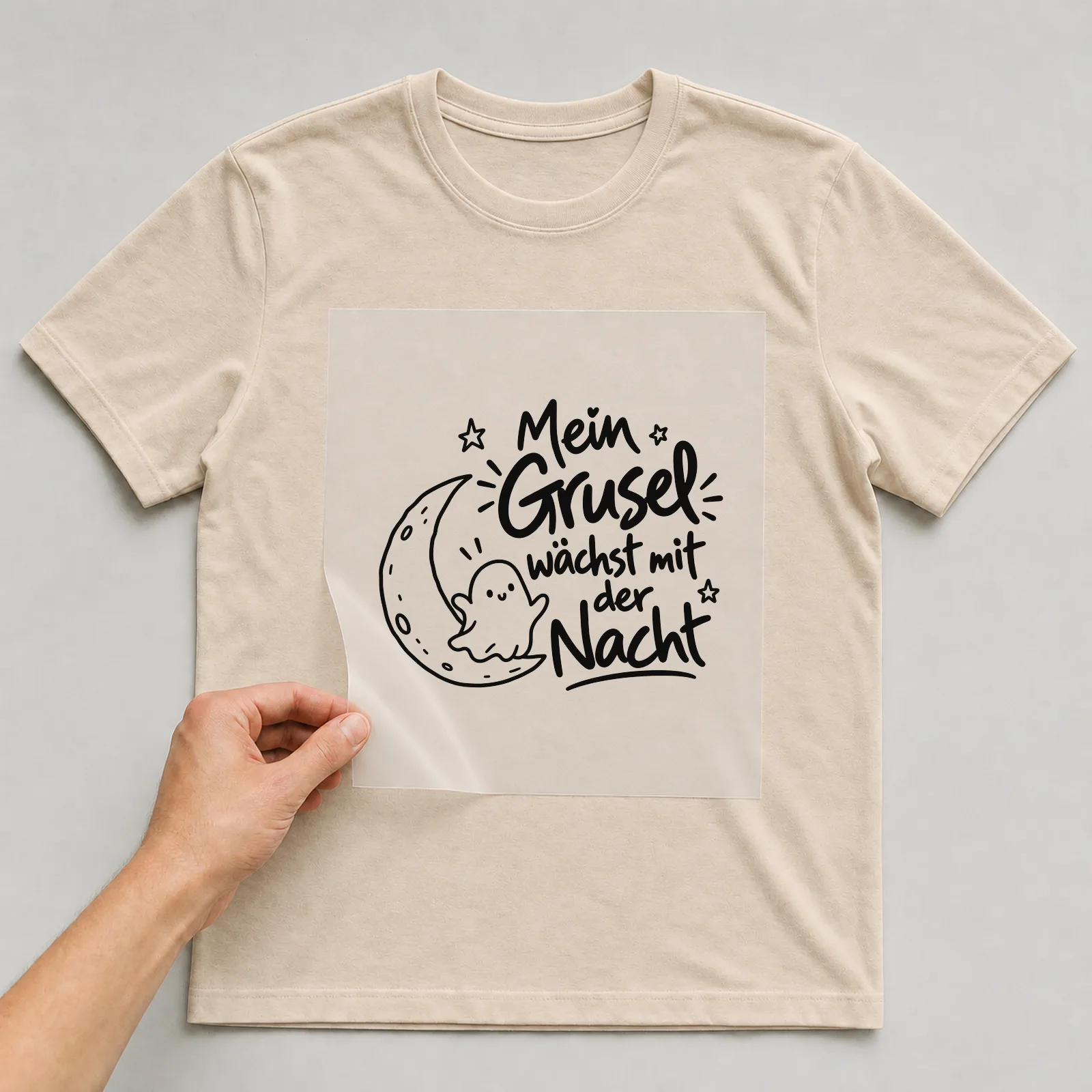 Bügelbild „Mein Grusel wächst mit der Nacht“ auf beigem T-Shirt, Folie wird aufgelegt