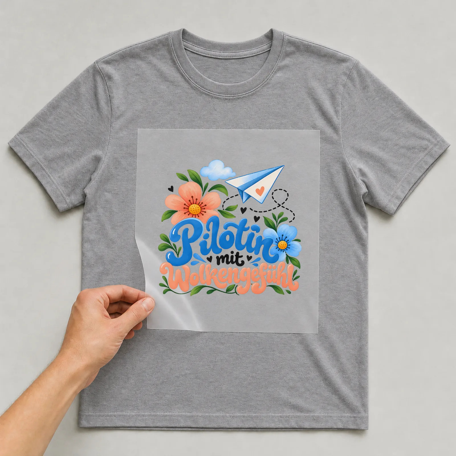 Bügelbild „Pilotin mit Wolkengefühl“ auf grauem T-Shirt, Folie wird aufgelegt