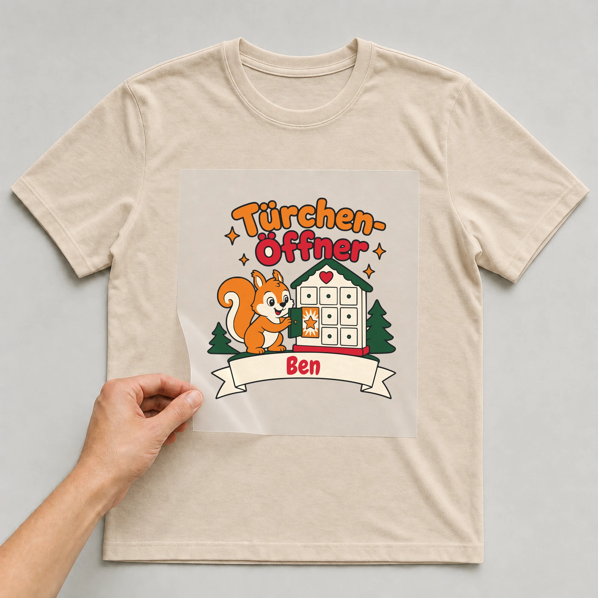 Bügelbild Türchen-Öffner mit Name auf beigem T-Shirt, Folie wird aufgelegt