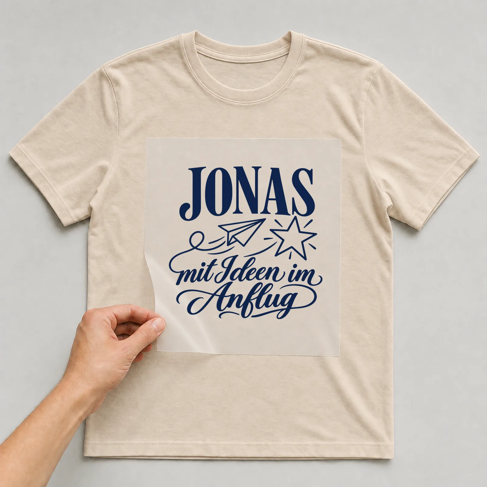 Bügelbild „Jonas mit Ideen im Anflug“ auf beigem T-Shirt, Folie wird aufgelegt
