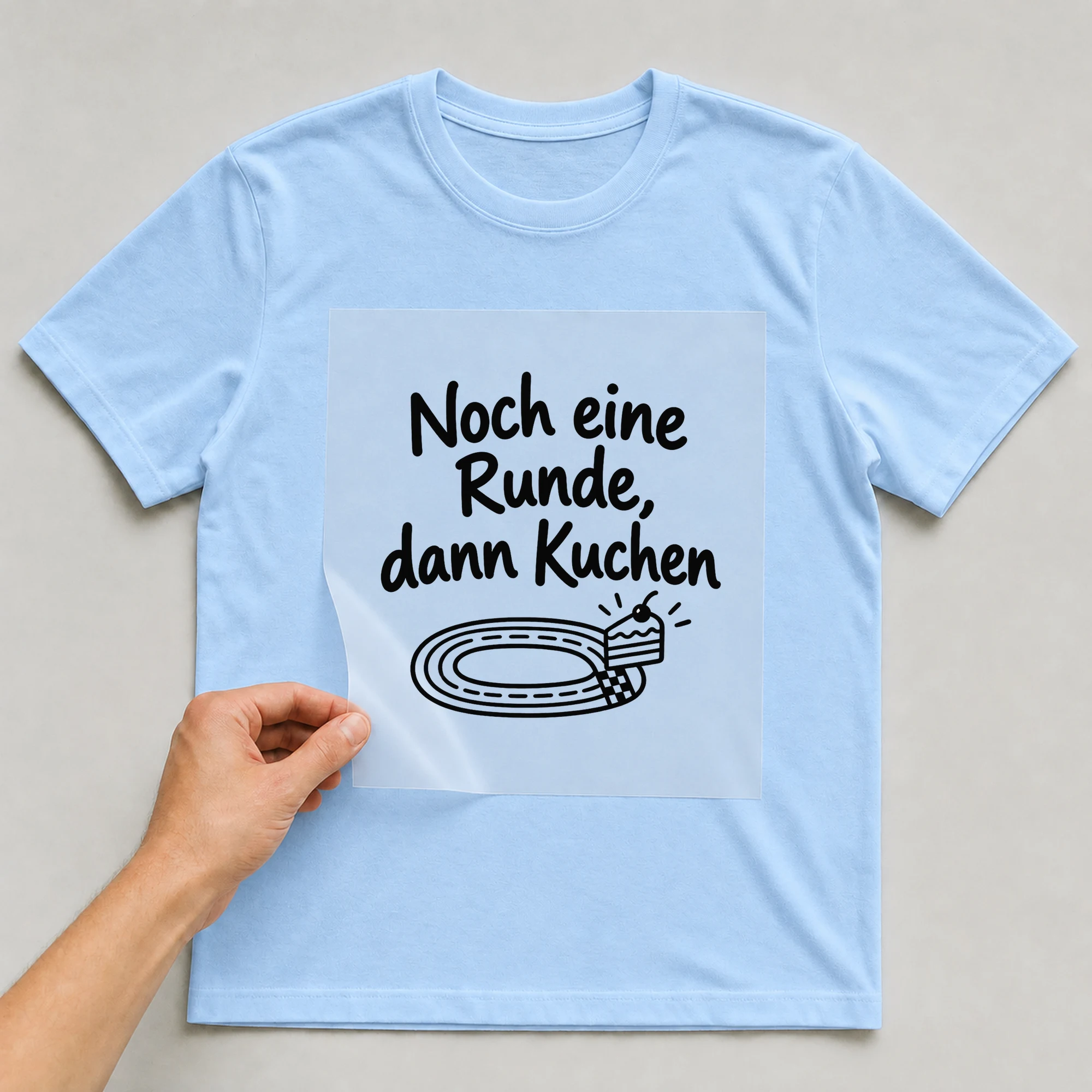 Bügelbild „Noch eine Runde, dann Kuchen“ auf babyblauem T-Shirt, Folie wird aufgelegt