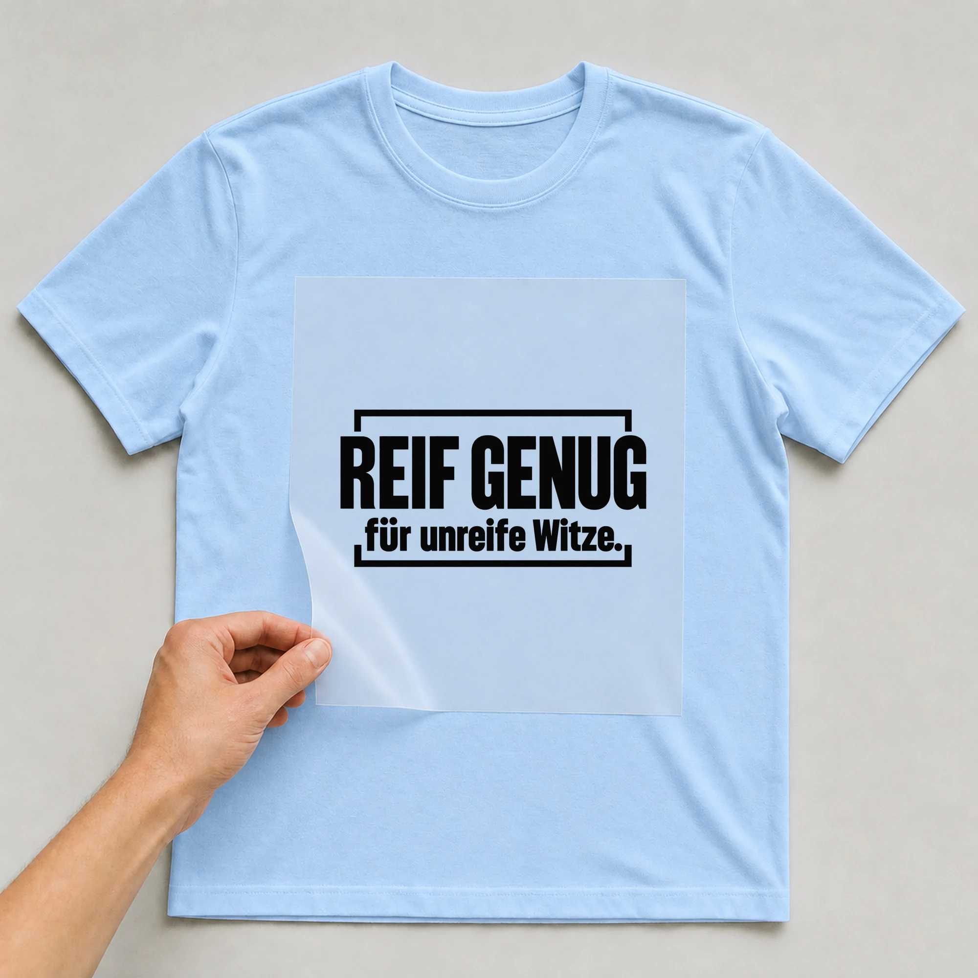 Bügelbild „Reif genug für unreife Witze.“ auf babyblauem T-Shirt, Folie wird aufgelegt