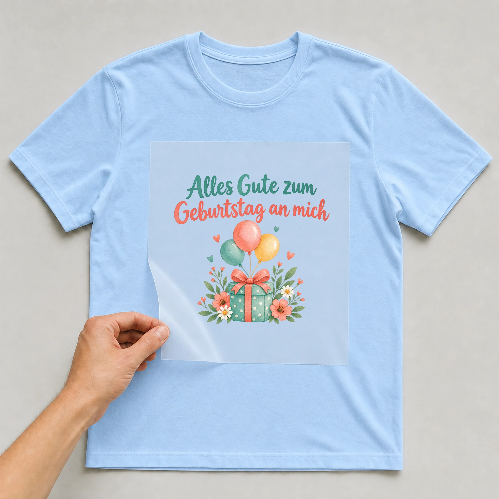 Bügelbild „Alles Gute zum Geburtstag an mich“ auf babyblauem T-Shirt, Folie wird aufgelegt