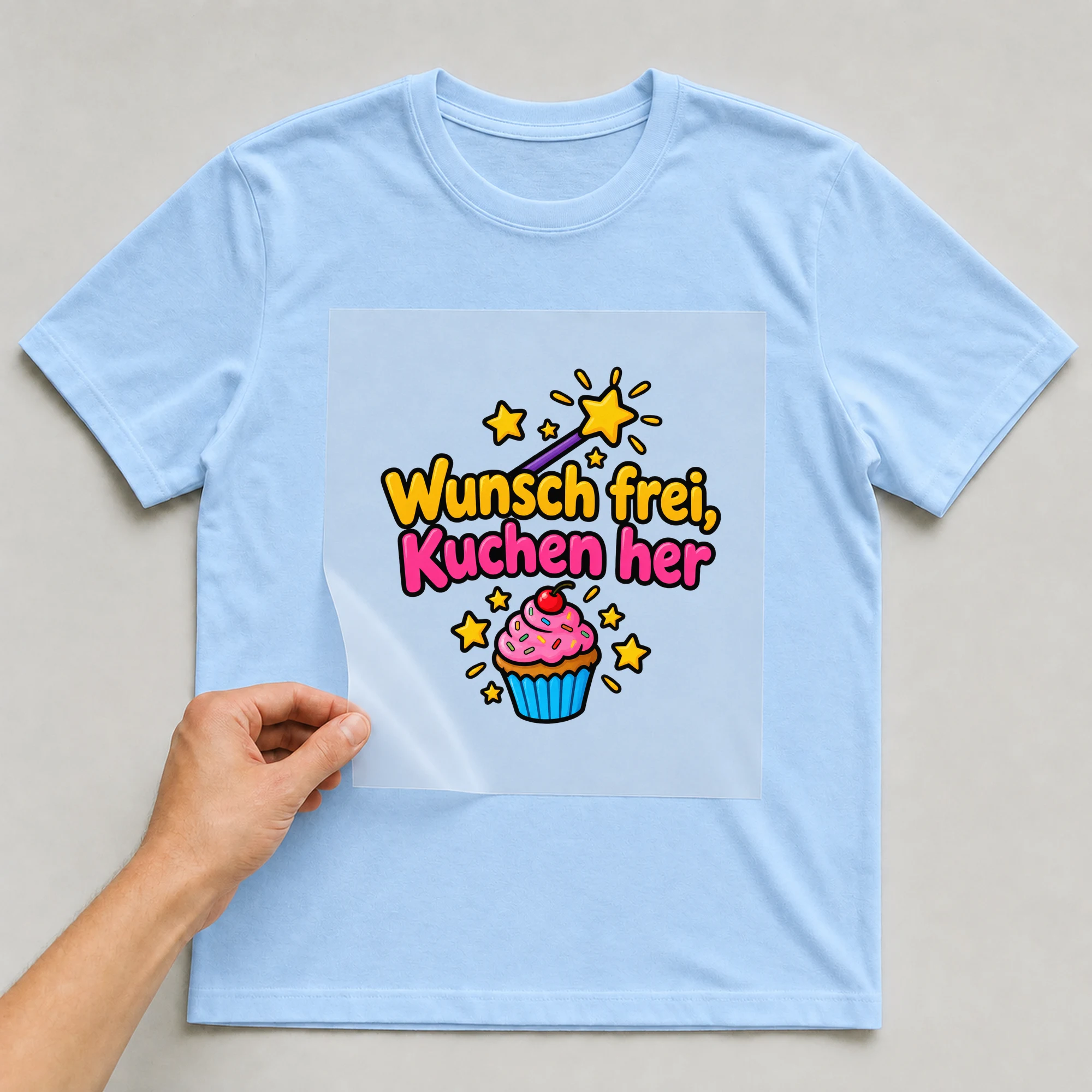 Bügelbild „Wunsch frei kuchen her“ auf babyblauem T-Shirt, Folie wird aufgelegt