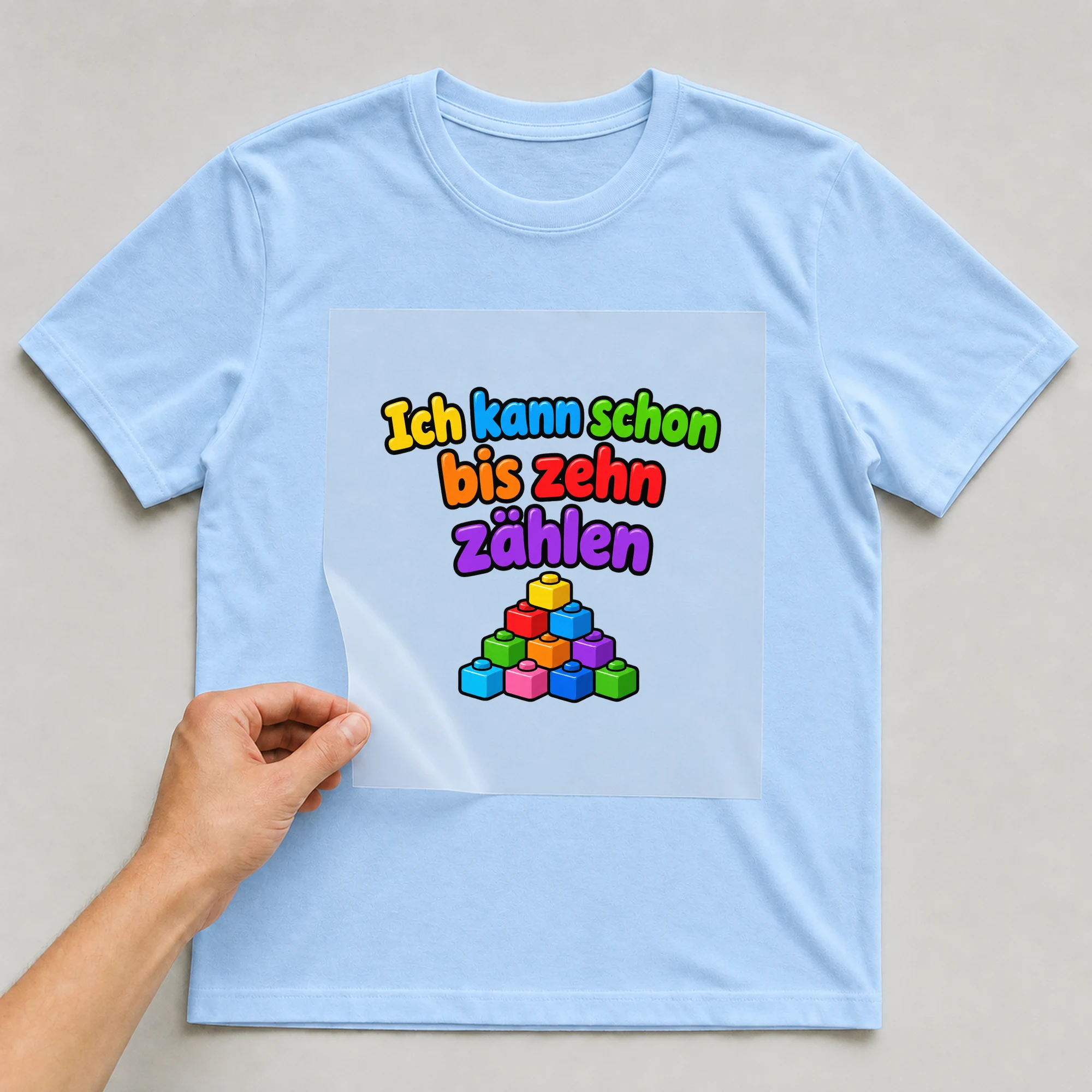 Bügelbild „Ich kann schon bis zehn zaehlen“ auf babyblauem T-Shirt, Folie wird aufgelegt