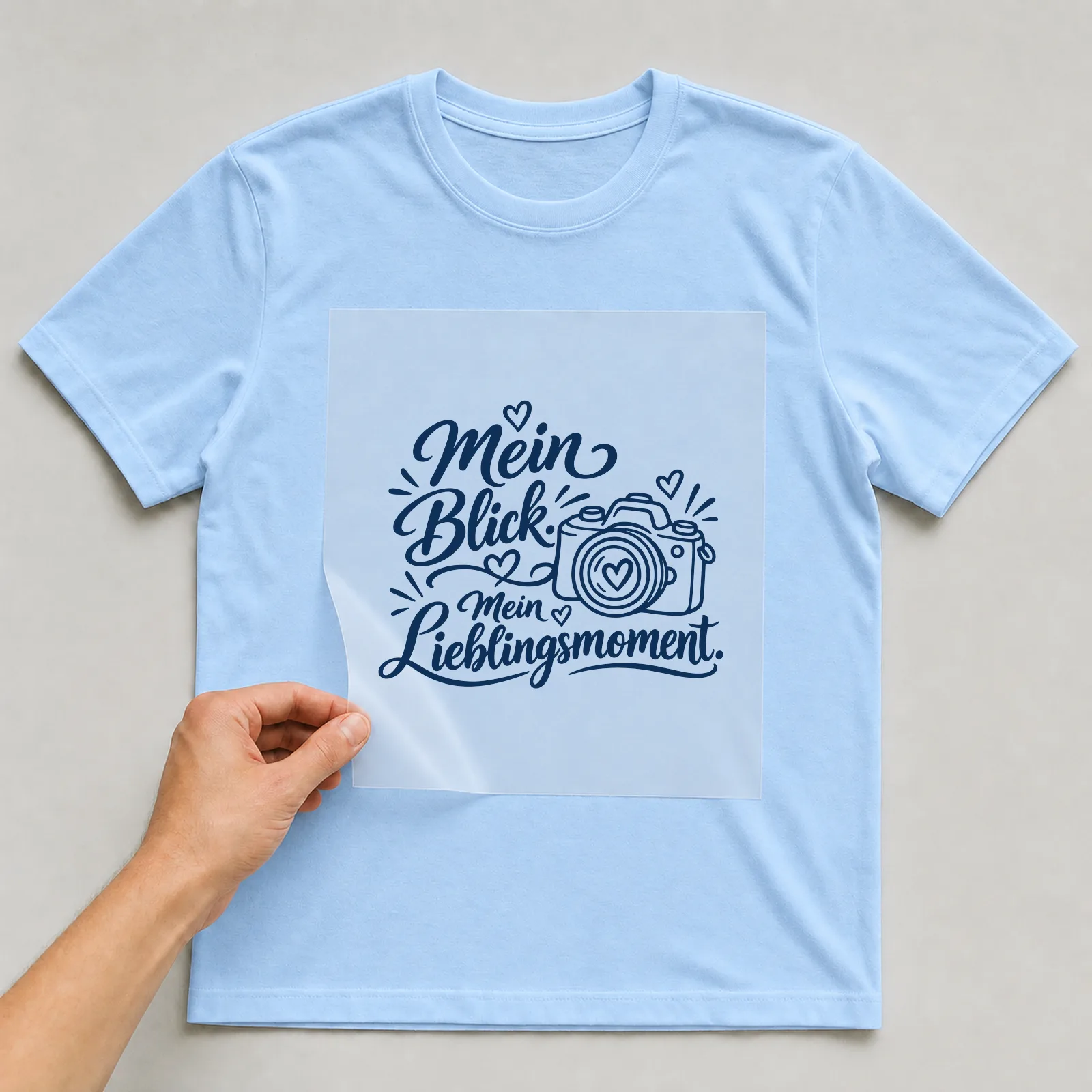 Bügelbild „Mein Blick. Mein Lieblingsmoment.“ auf hellblauem T-Shirt, Folie wird aufgelegt