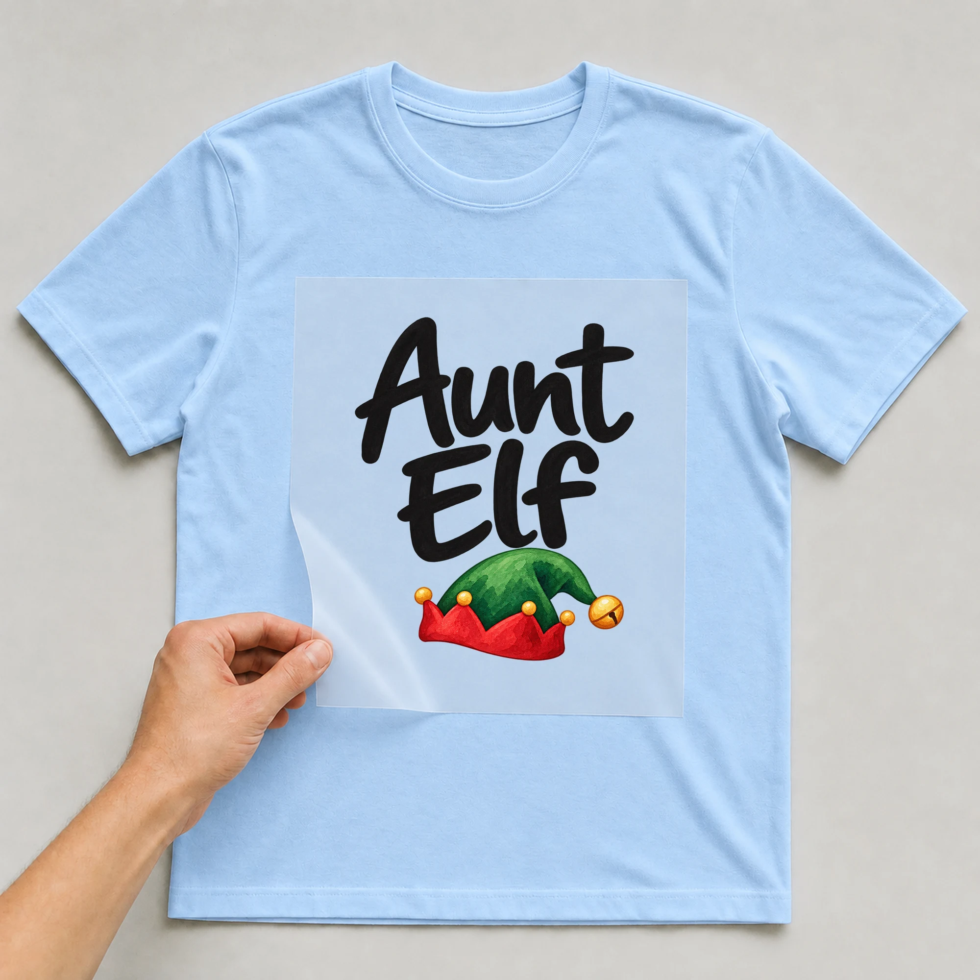 Bügelbild „Aunt Elf“ auf babyblauem T-Shirt, Folie wird aufgelegt
