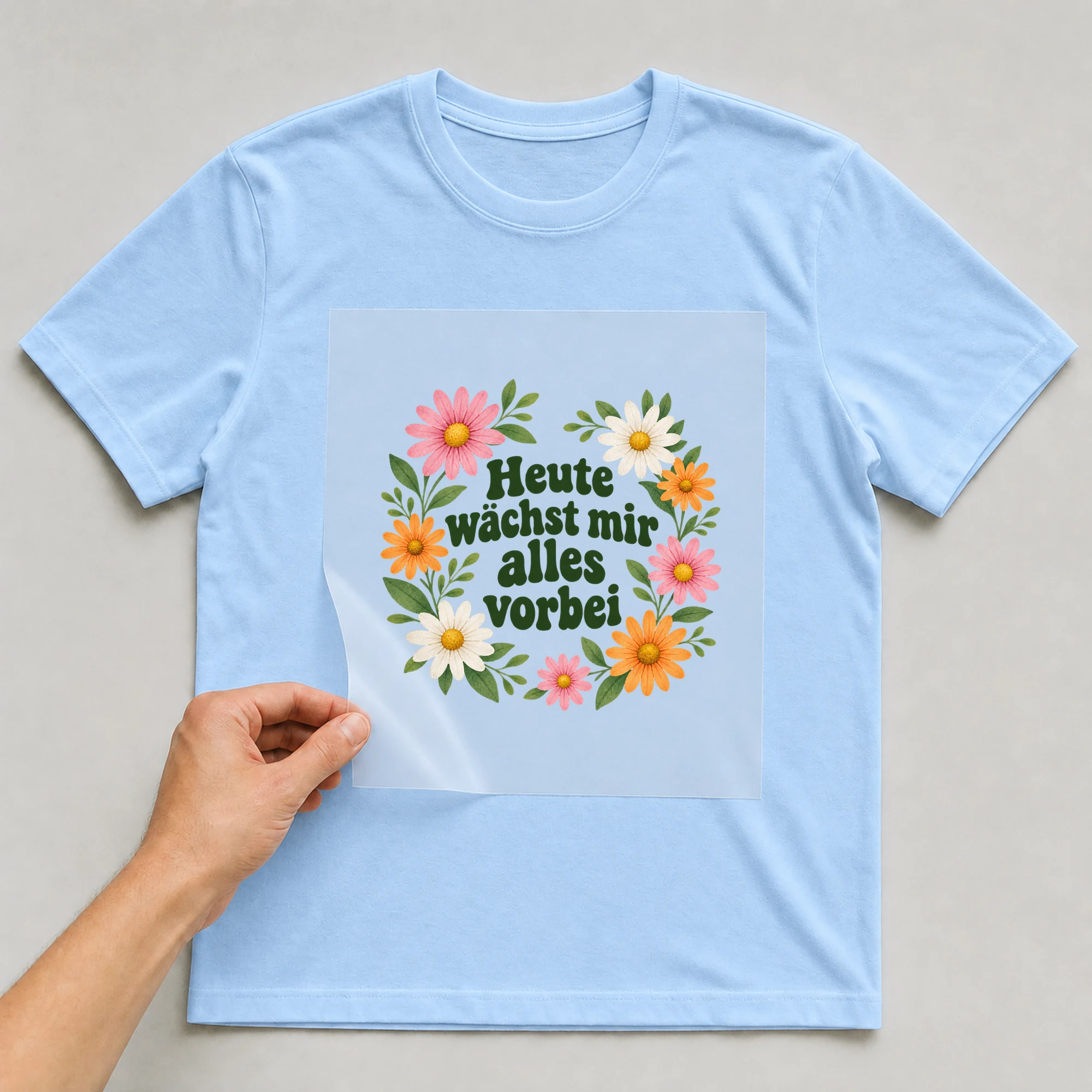 Bügelbild „Heute wächst mir alles vorbei“ auf hellblauem T-Shirt, Folie wird aufgelegt