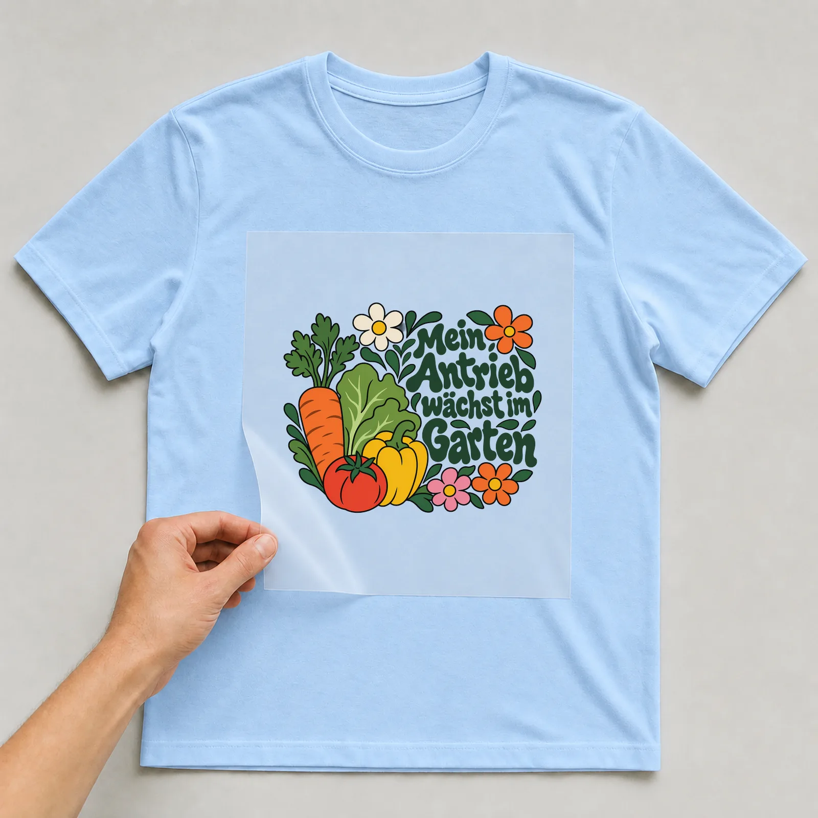 Bügelbild „Mein Antrieb wächst im Garten“ auf hellblauem T-Shirt, Folie wird aufgelegt
