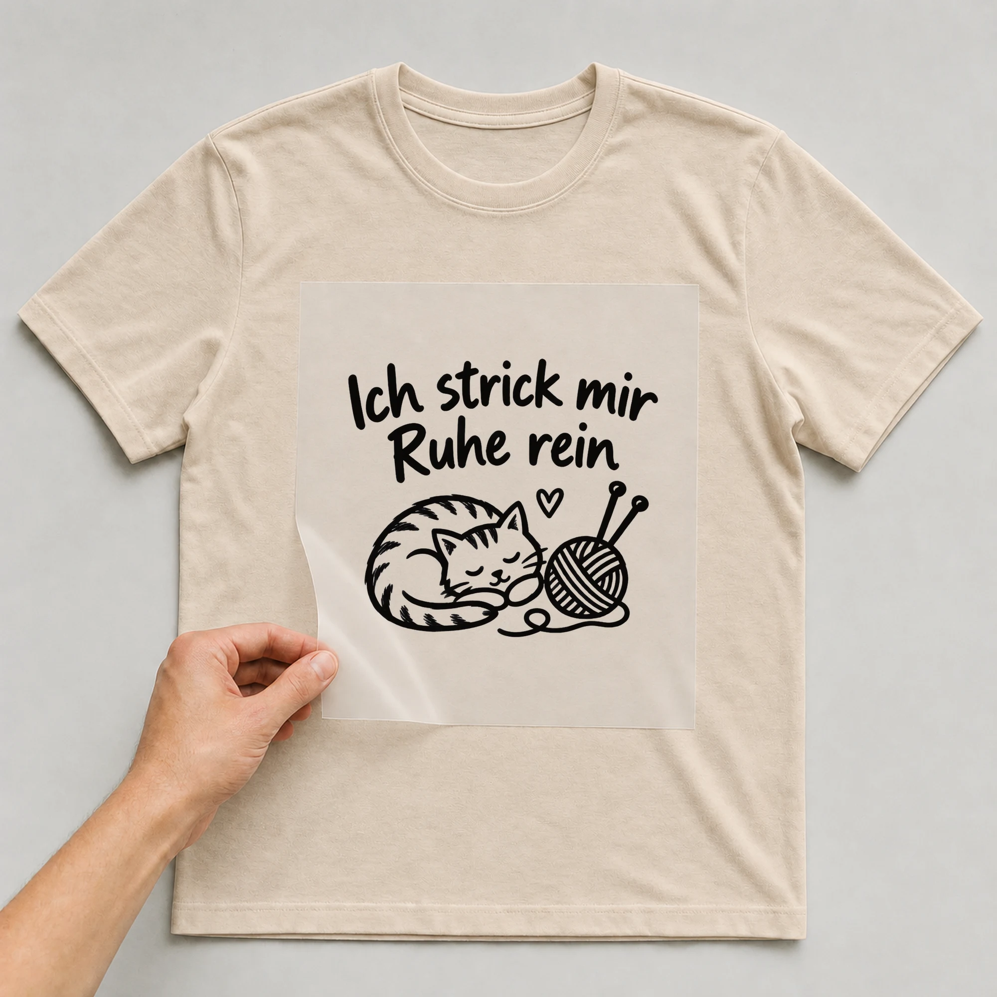 Bügelbild „Ich strick mir Ruhe rein“ auf beigem T-Shirt, Folie wird aufgelegt