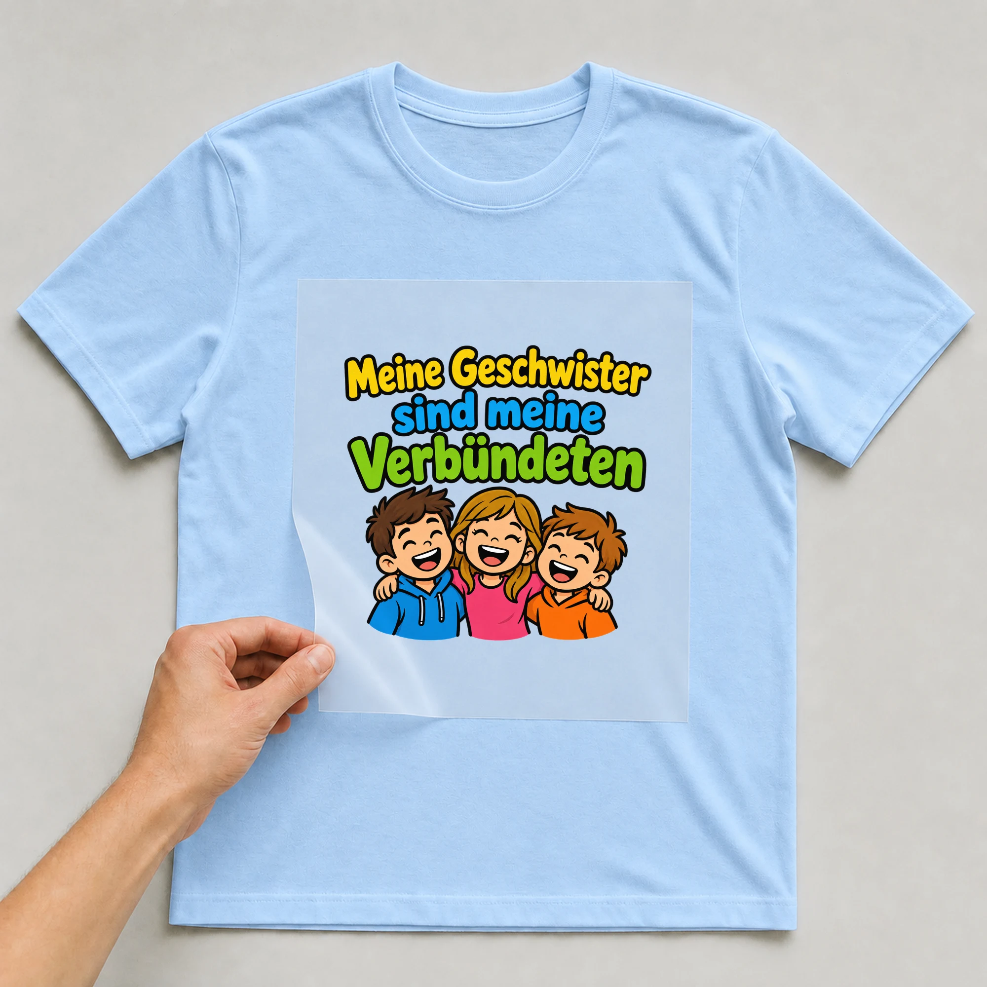 Bügelbild „Meine Geschwister sind meine Verbündeten“ auf babyblauem T-Shirt, Folie wird aufgelegt